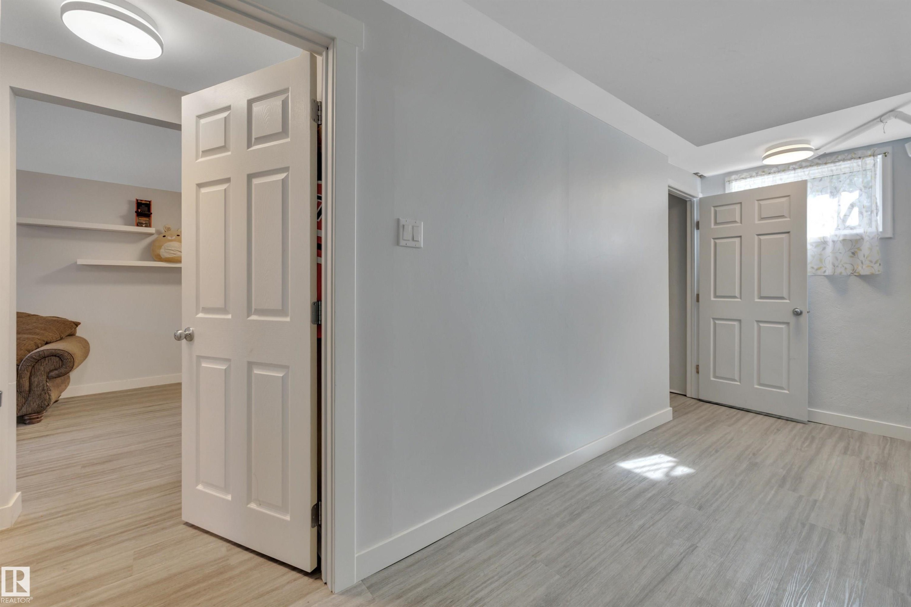Interior room featuring light wood-finish flooring, light grey walls, and white baseboards - 9835 74 Street, Edmonton, AB