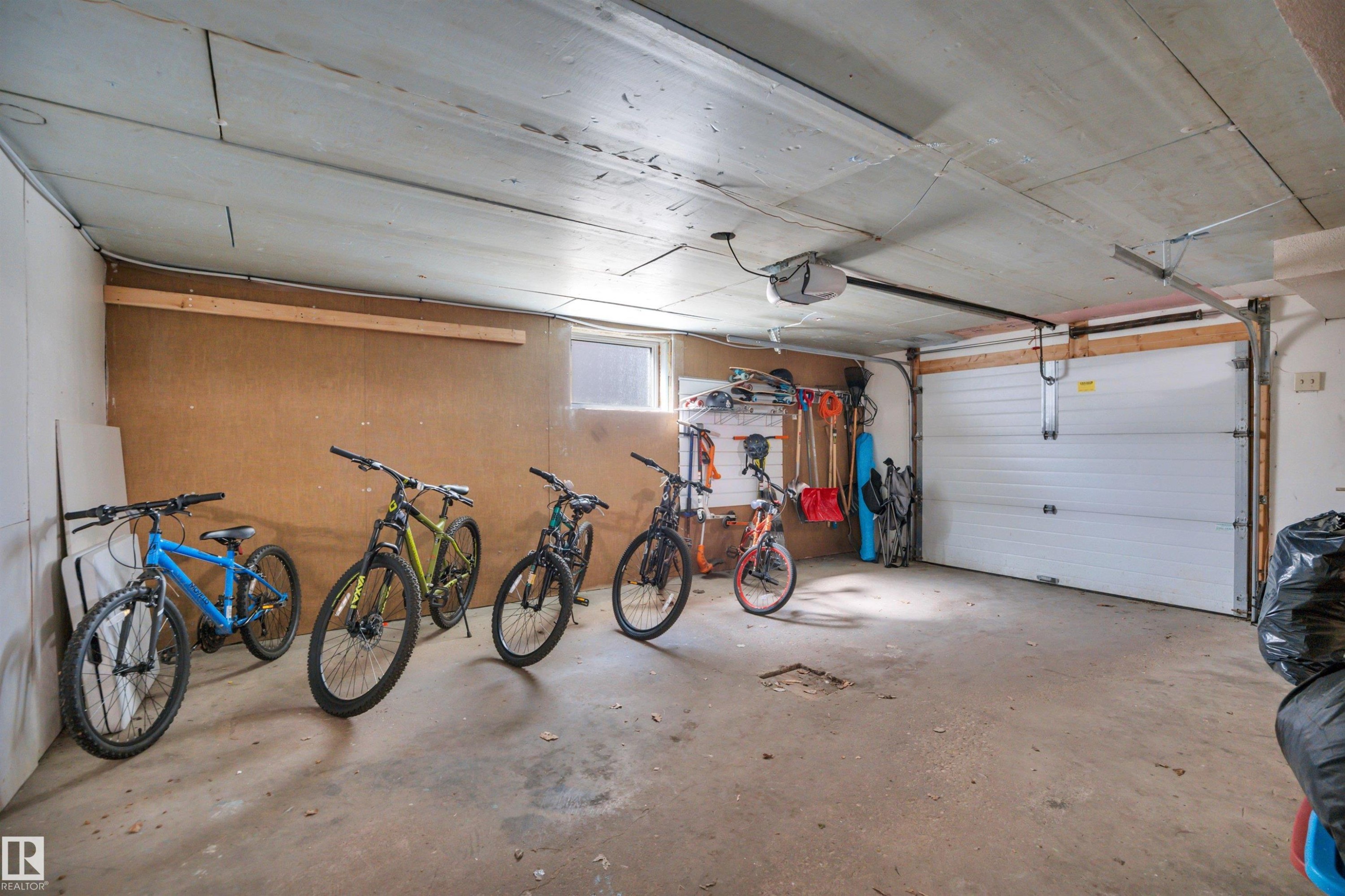 Attached garage featuring a white sectional door, concrete flooring, and a remote-controlled opener - 9835 74 Street, Edmonton, AB