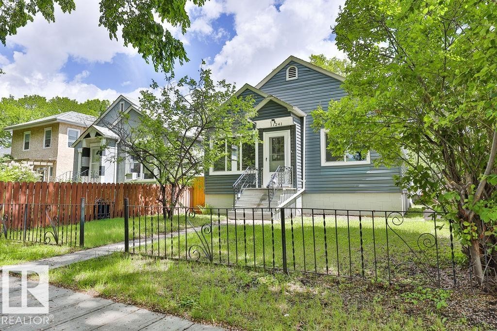 Blue siding exterior with a prominent front entry featuring white trim and a gabled porch roof - 11241 88 Street, Edmonton, AB