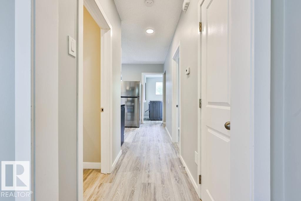 Hallway featuring wood-finish flooring, recessed lighting, and crisp white trim - 11241 88 Street, Edmonton, AB