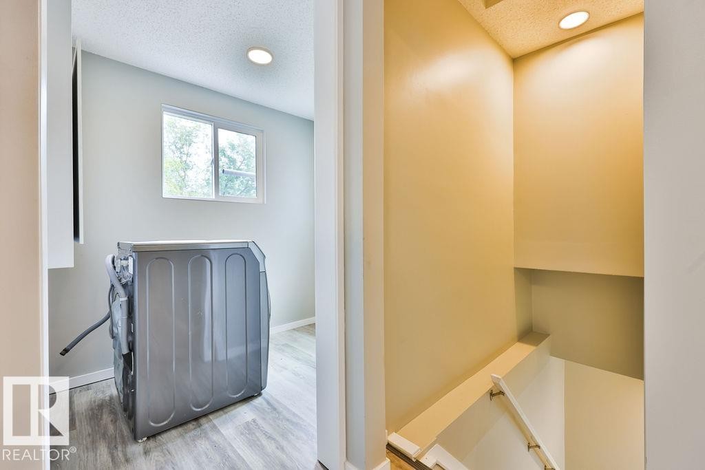 Laundry area featuring a window, recessed lighting, and wood-finish flooring - 11241 88 Street, Edmonton, AB