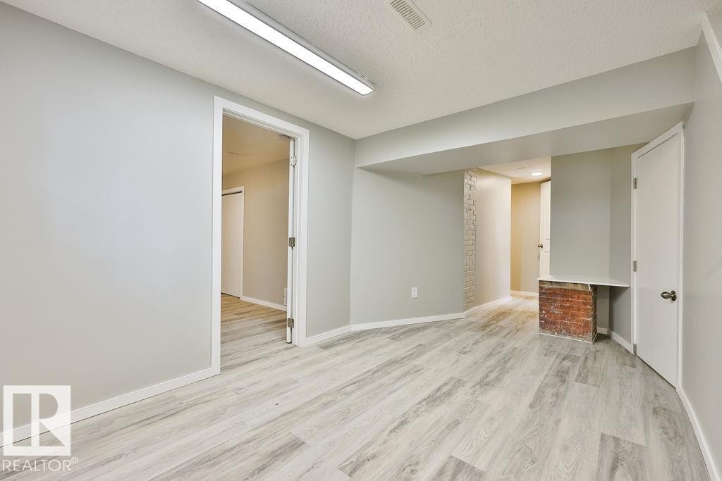 Spacious room featuring light wood-finish flooring, light gray wall paint, white trim, and recessed lighting - 11241 88 Street, Edmonton, AB