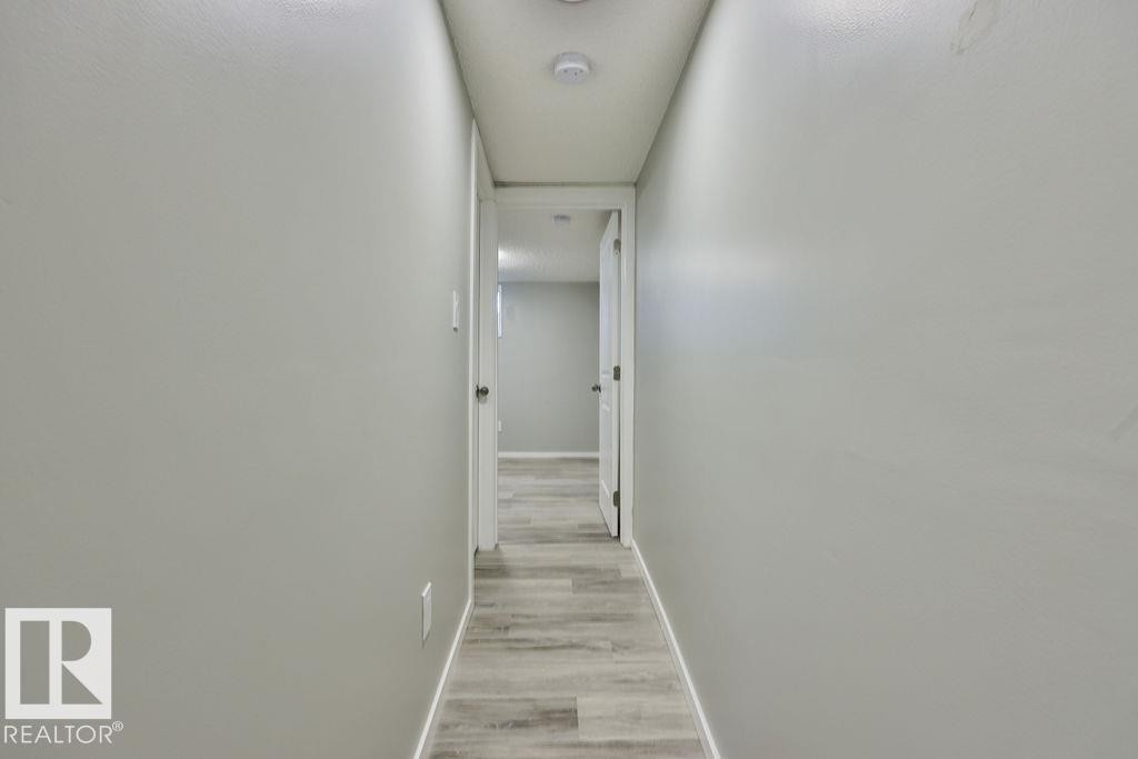 Hallway featuring light gray walls, recessed lighting, and wood-finish flooring - 11241 88 Street, Edmonton, AB