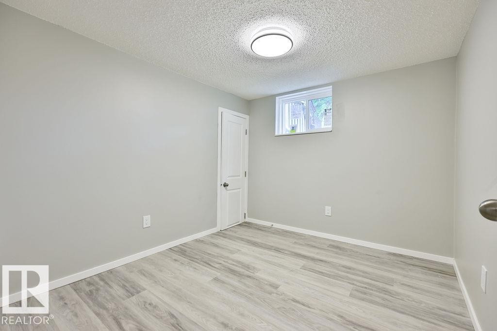 Room featuring light gray walls, white trim, and wood-finish flooring - 11241 88 Street, Edmonton, AB