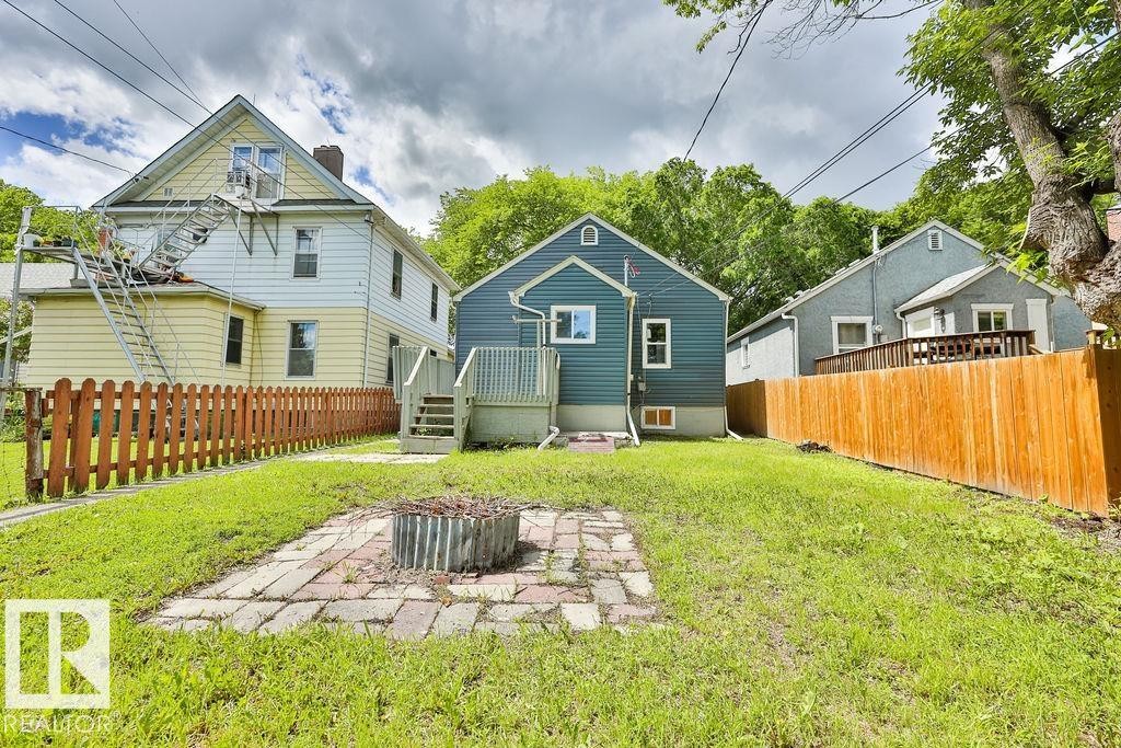 Expansive grass lawn featuring a brick paver patio with a fire pit - 11241 88 Street, Edmonton, AB