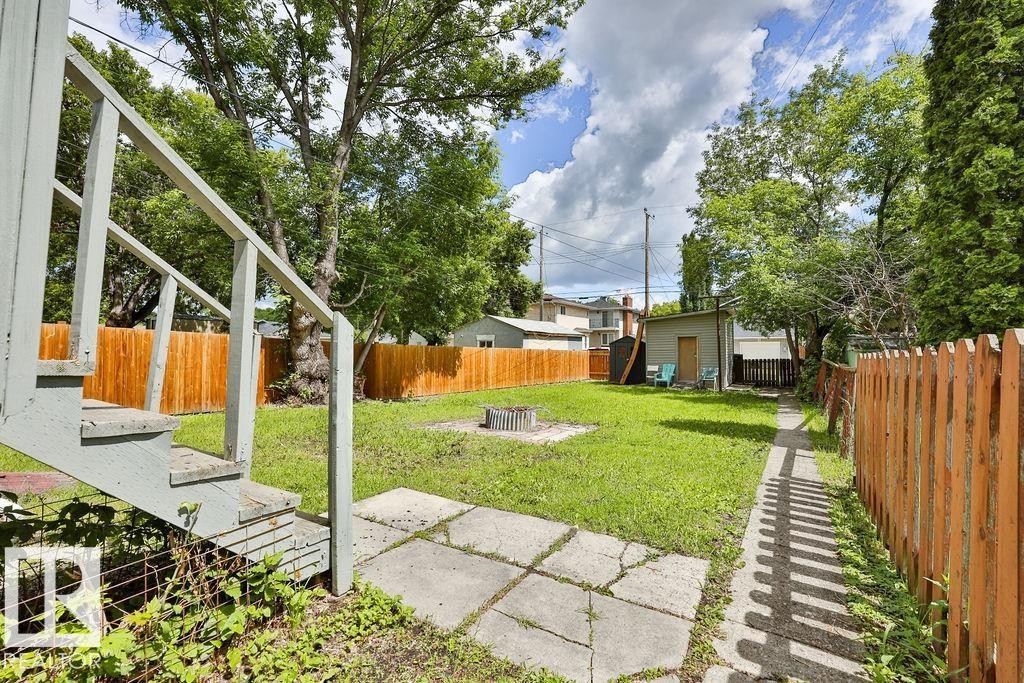Expansive backyard featuring a lush lawn, a fire pit, and a small utility shed - 11241 88 Street, Edmonton, AB