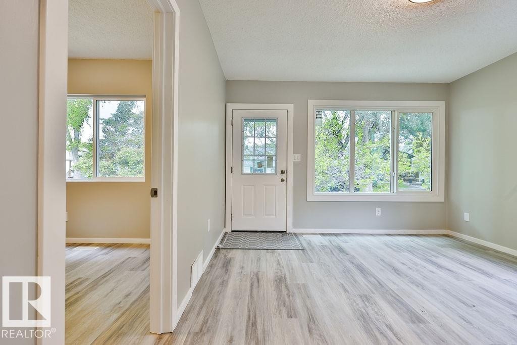 Entryway featuring a white paneled door with glass inserts, wood-finish flooring, and light gray painted walls - 11241 88 Street, Edmonton, AB