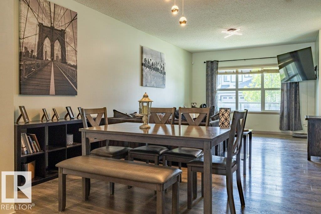 Spacious dining area featuring wood-finish flooring and a contemporary multi-bulb ceiling fixture - 17123 49 Street, Edmonton, AB