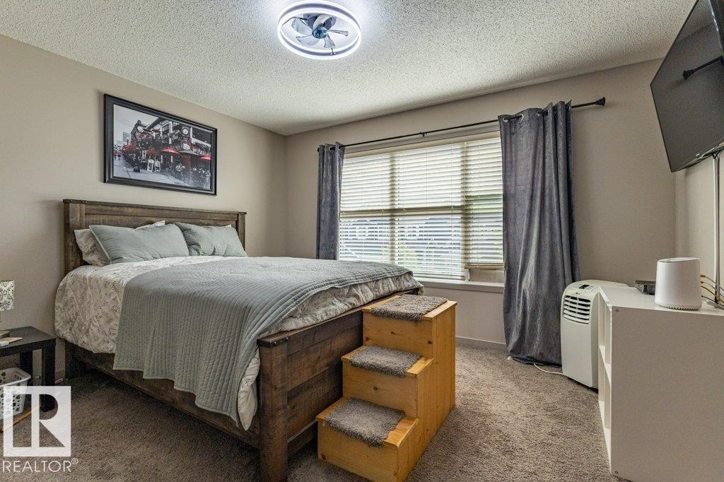 Bedroom featuring neutral-toned walls, textured carpeting, and a window with blinds and drapes - 17123 49 Street, Edmonton, AB
