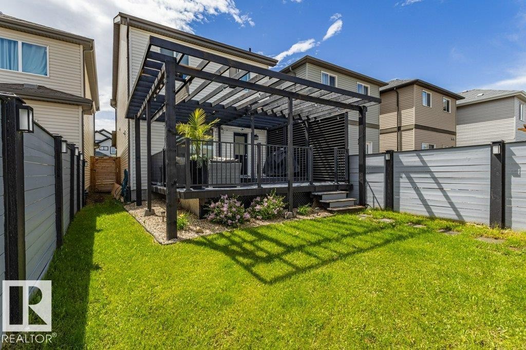 Expansive green lawn with a dark wood pergola covering a raised deck - 17123 49 Street, Edmonton, AB