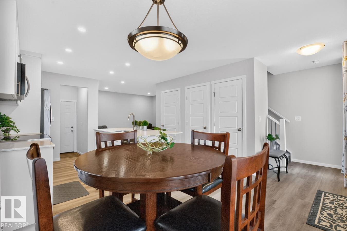 Dining area featuring a circular wood-finish table, overhead drum pendant light, and recessed lighting - 1022 Hearthstone Boulevard, Sherwood Park, AB
