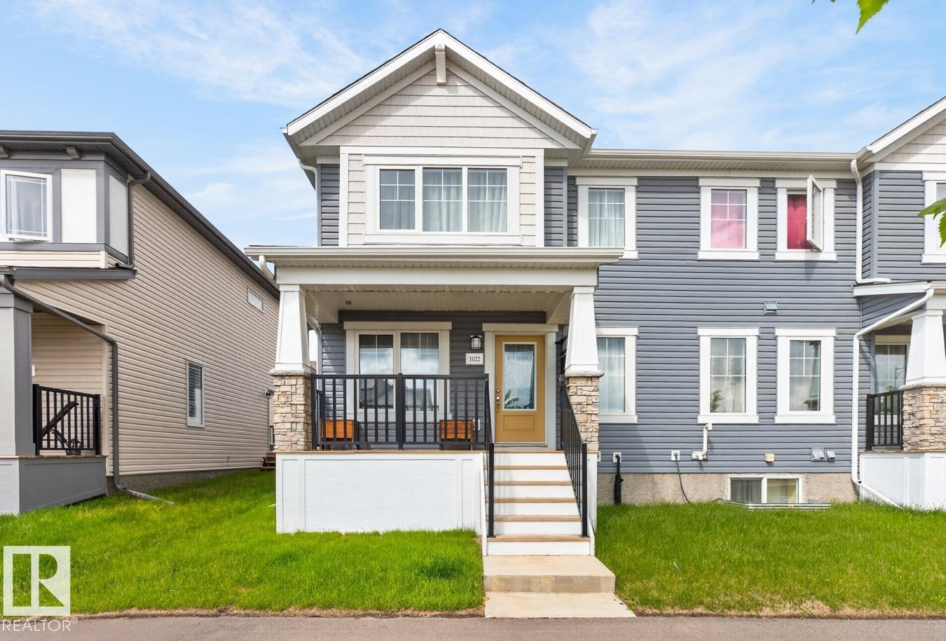 Grey siding exterior featuring a covered front porch with stone pillar accents - 1022 Hearthstone Boulevard, Sherwood Park, AB