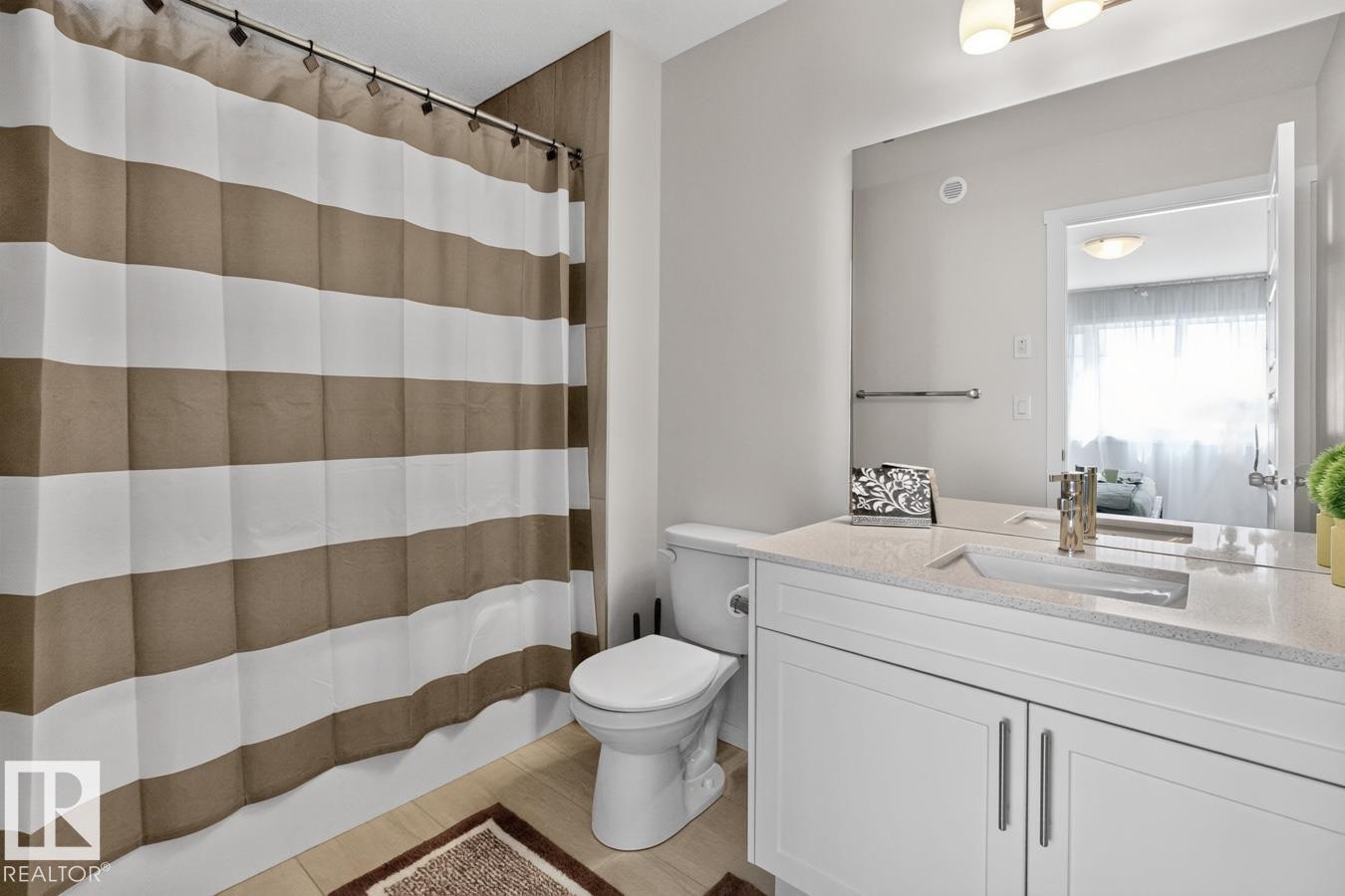 Bathroom featuring a white vanity with a light-toned countertop, an integrated sink with a polished chrome faucet, and a large wall-mounted mirror - 1022 Hearthstone Boulevard, Sherwood Park, AB