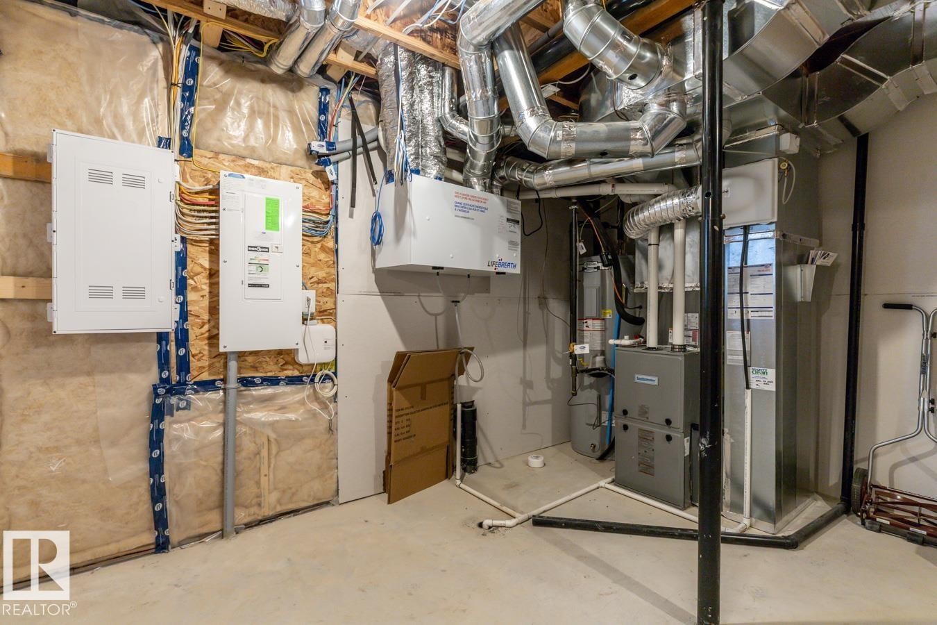Utility space featuring exposed ductwork, two white electrical panels, a water heater, and a furnace - 1022 Hearthstone Boulevard, Sherwood Park, AB