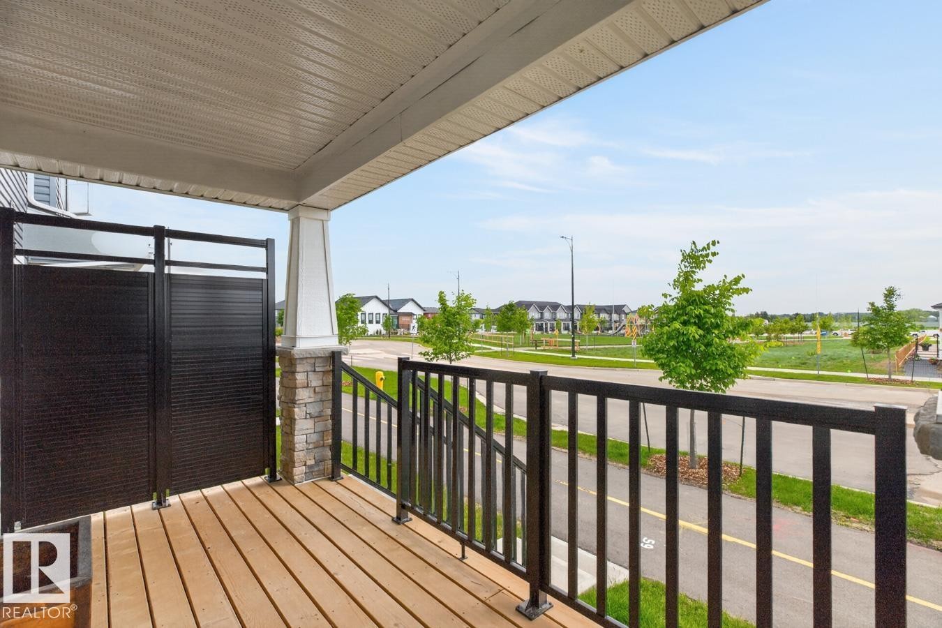 Front porch featuring wood-finish decking, black metal railings, and a privacy screen - 1022 Hearthstone Boulevard, Sherwood Park, AB