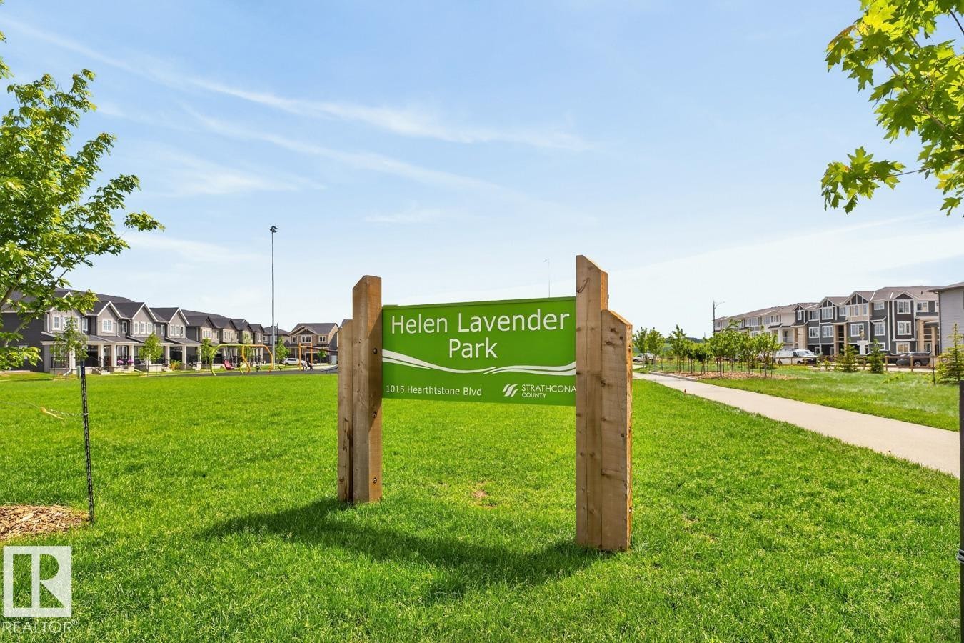 Green space featuring a park sign, a paved walking path, and a backdrop of contemporary residential architecture - 1022 Hearthstone Boulevard, Sherwood Park, AB