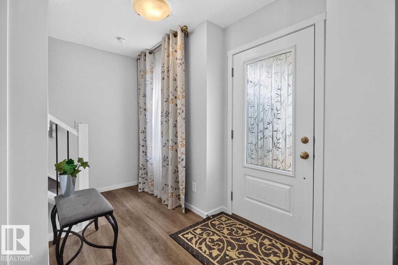 Entryway featuring a white paneled door with decorative frosted glass, overhead flush-mount lighting, and wood-finish flooring - 1022 Hearthstone Boulevard, Sherwood Park, AB