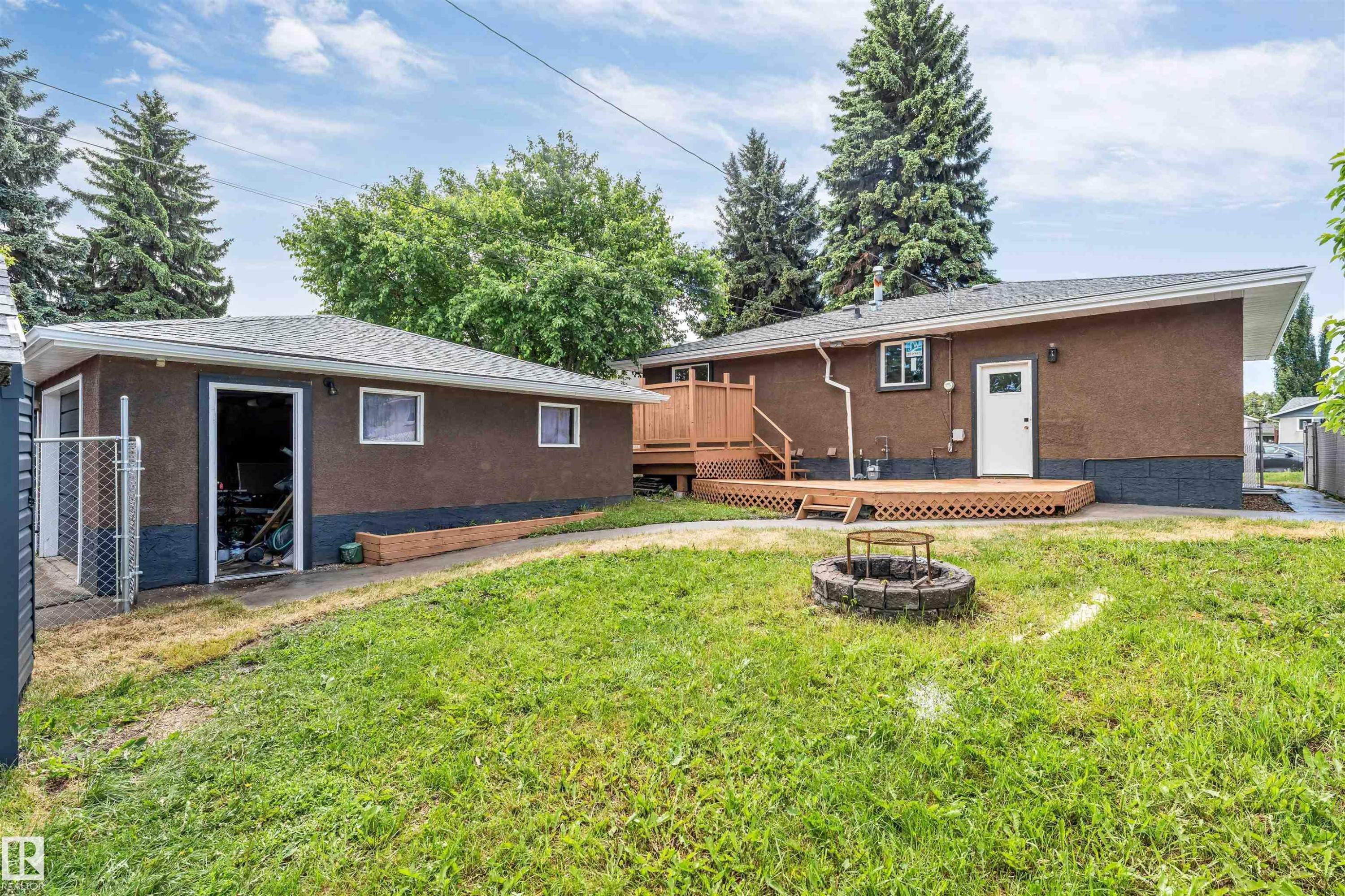 Expansive backyard featuring a detached garage with a single vehicle bay, a wood deck, and a built-in fire pit - 6404 88 Avenue, Edmonton, AB