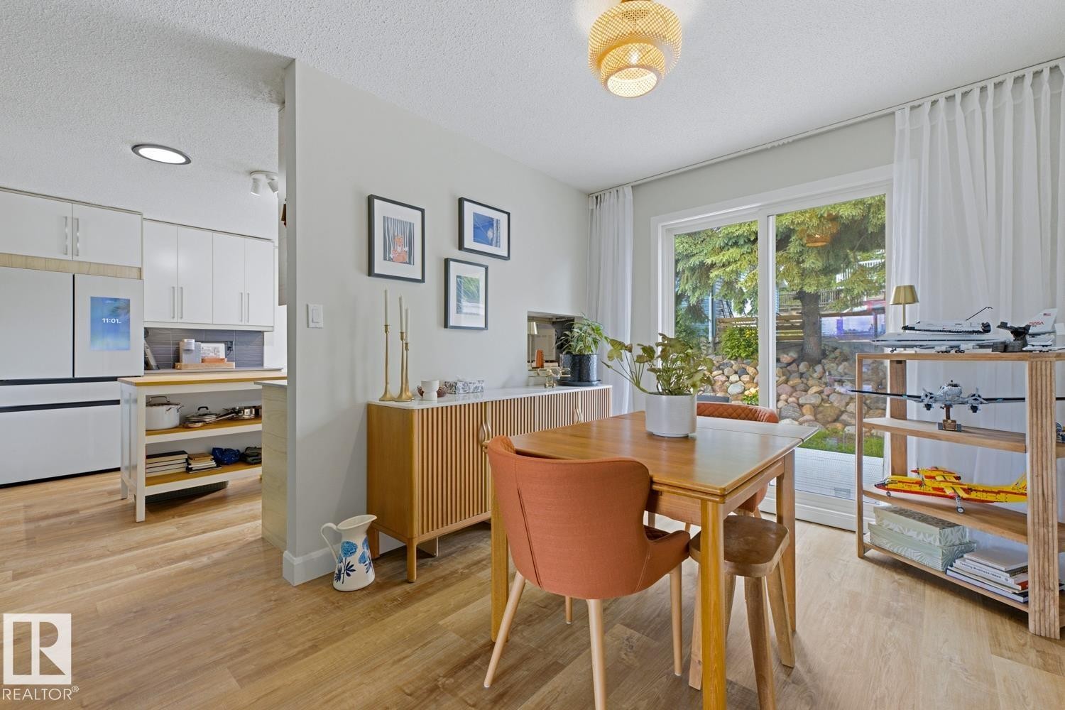 Bright dining area featuring wood-finish flooring and a contemporary light fixture - 3504 102 Avenue, Edmonton, AB