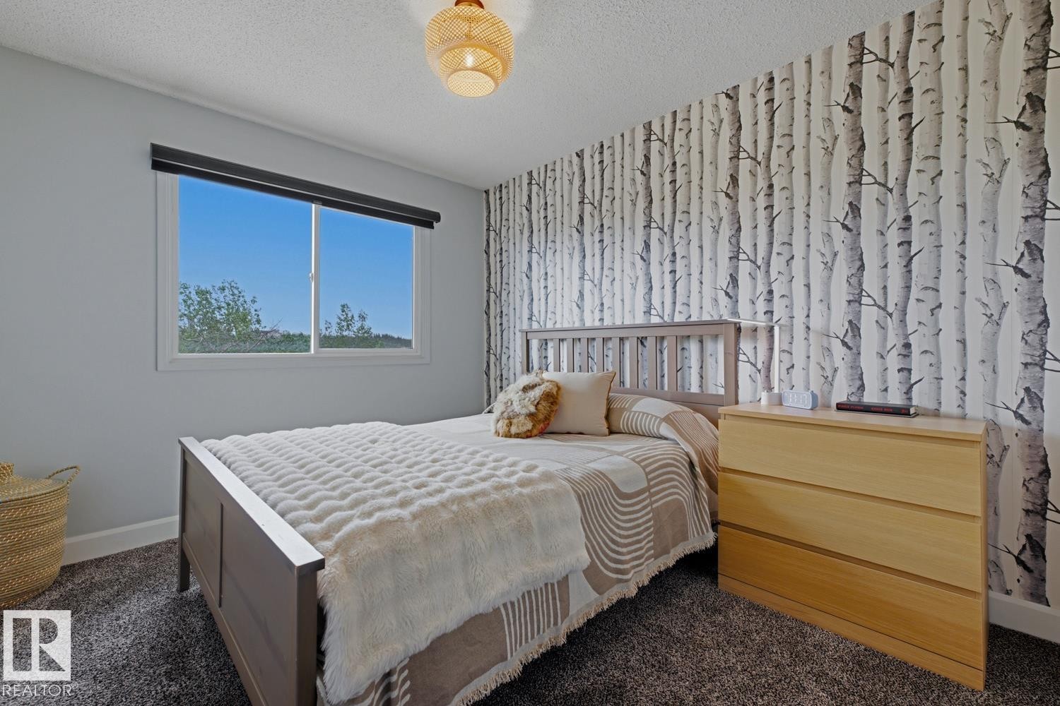 Room featuring a window with roller shade, textured wallpaper, carpeted flooring, and a ceiling-mounted light fixture - 3504 102 Avenue, Edmonton, AB