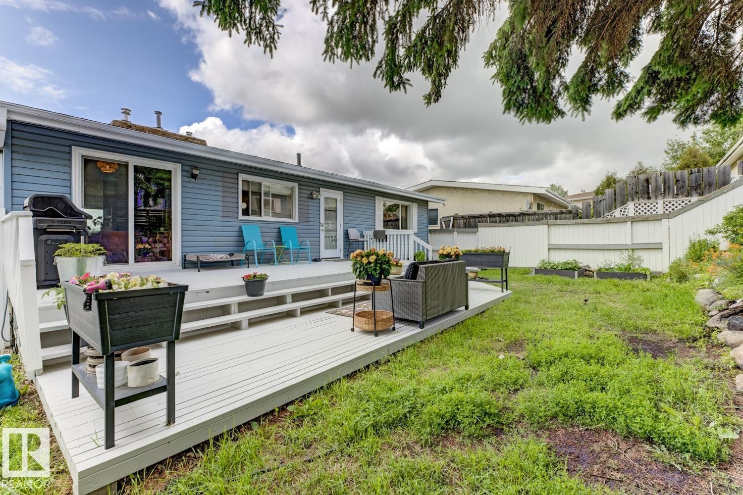 Rear exterior showcasing a multi-level deck with white railings, a sliding glass door, and a separate entry door - 3504 102 Avenue, Edmonton, AB