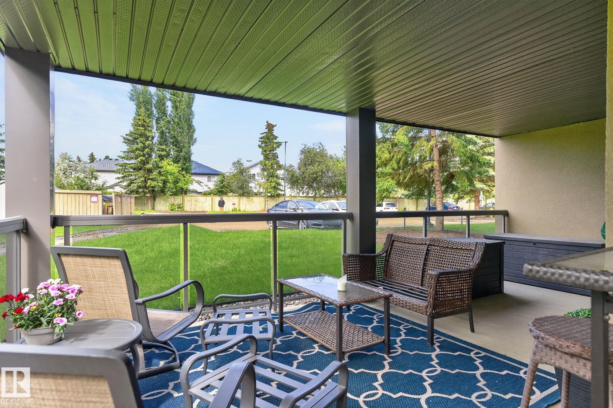 Covered patio featuring a solid ceiling, concrete flooring, and a glass panel railing system - 122 279 Suder Greens Drive, Edmonton, AB