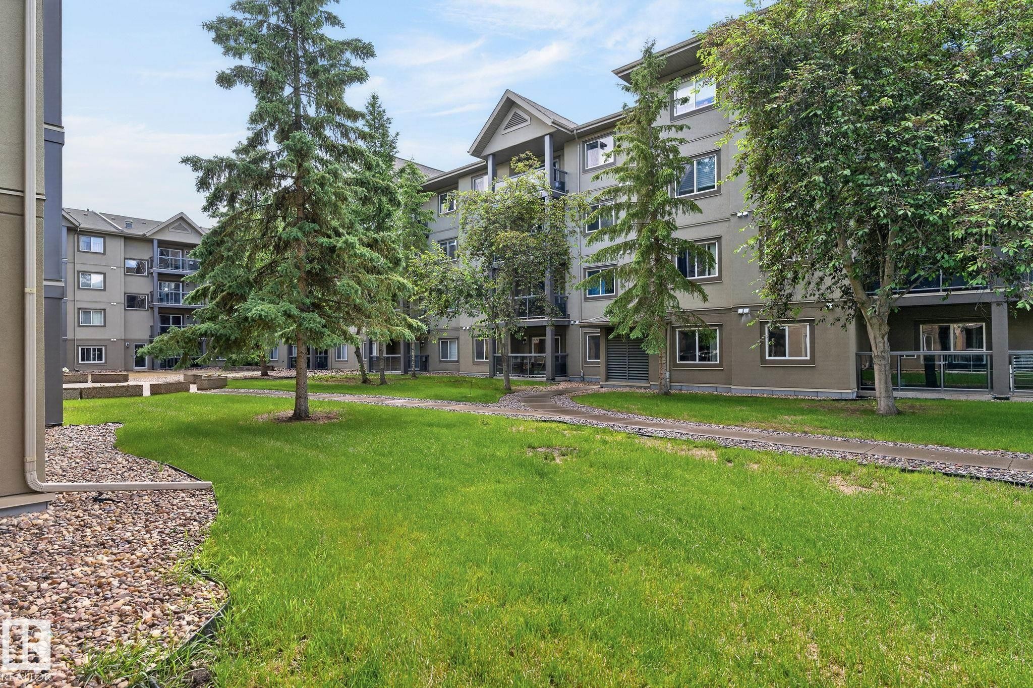 Central green space surrounded by multi-story residential buildings - 122 279 Suder Greens Drive, Edmonton, AB