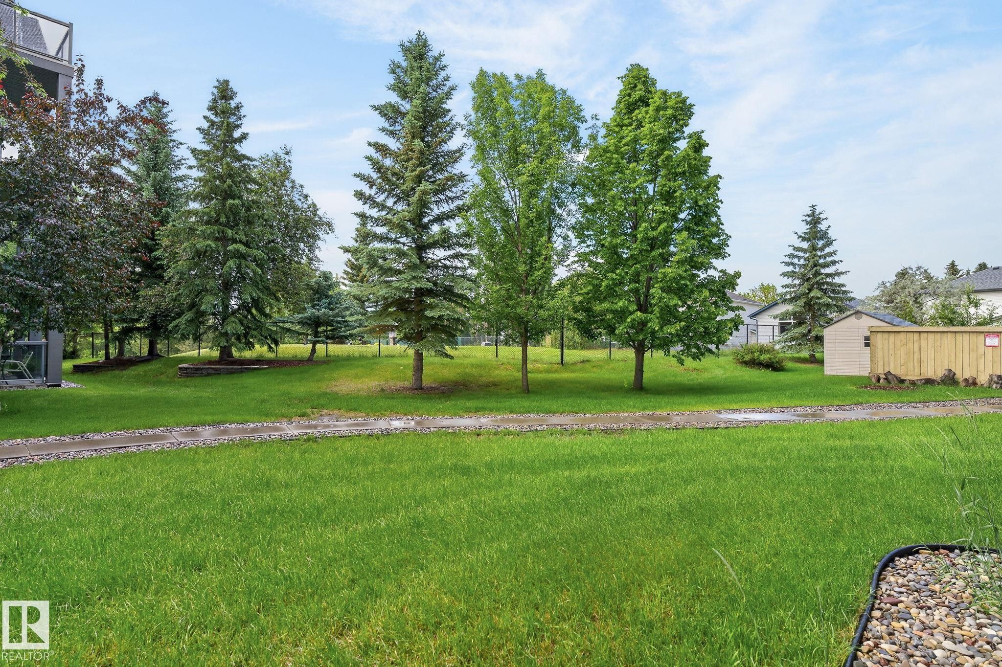 Expansive green space featuring mature trees and a gravel pathway - 122 279 Suder Greens Drive, Edmonton, AB