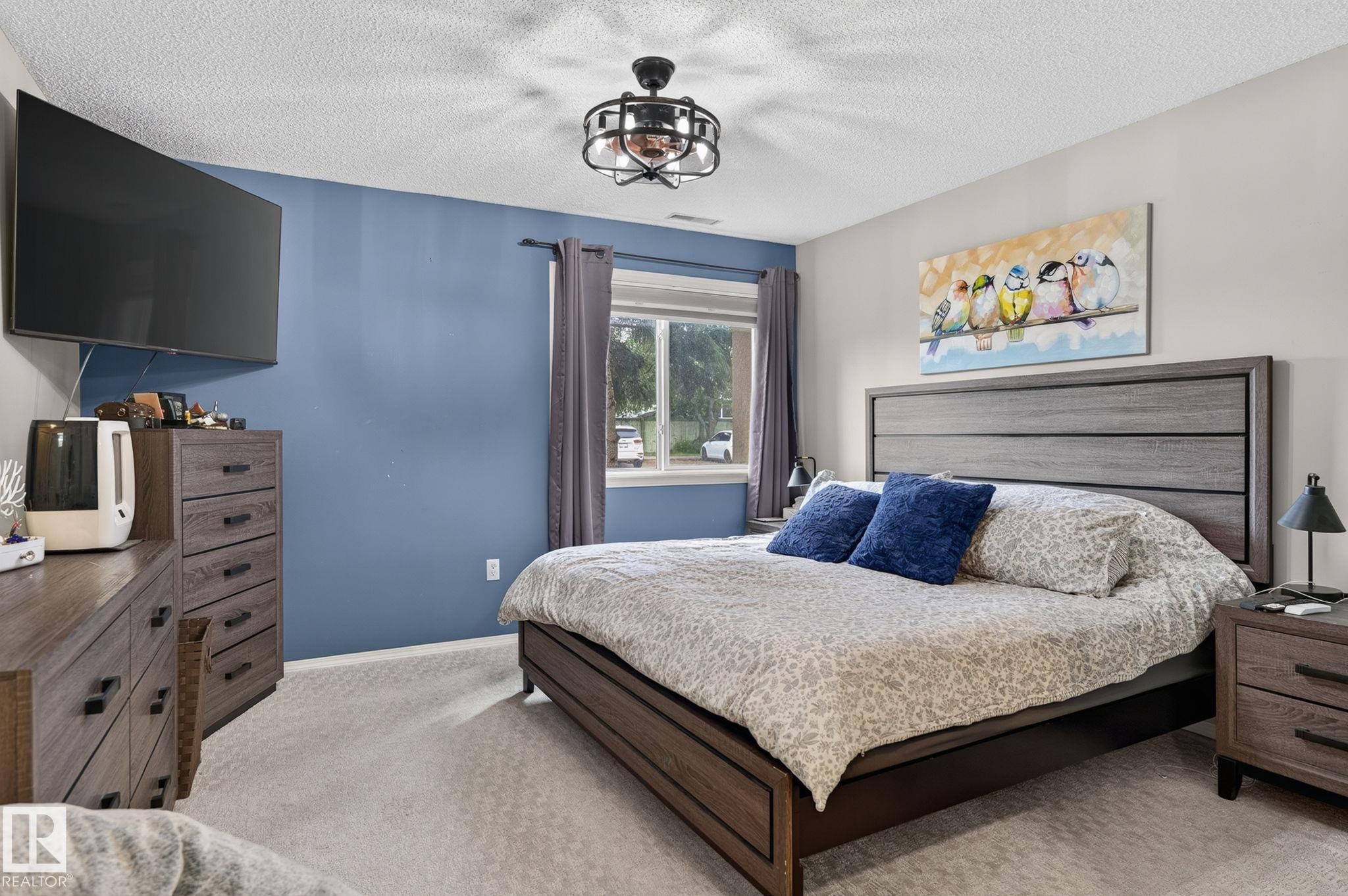 Carpeted room featuring a ceiling fan with integrated lighting, a window with drapery, and painted walls - 122 279 Suder Greens Drive, Edmonton, AB