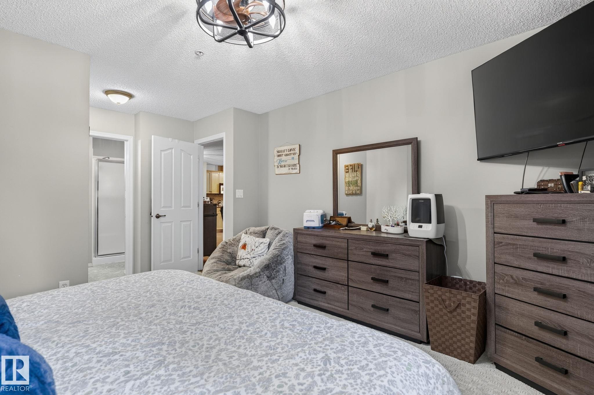 Bedroom featuring light gray wall paint, textured ceiling, and carpeted flooring - 122 279 Suder Greens Drive, Edmonton, AB