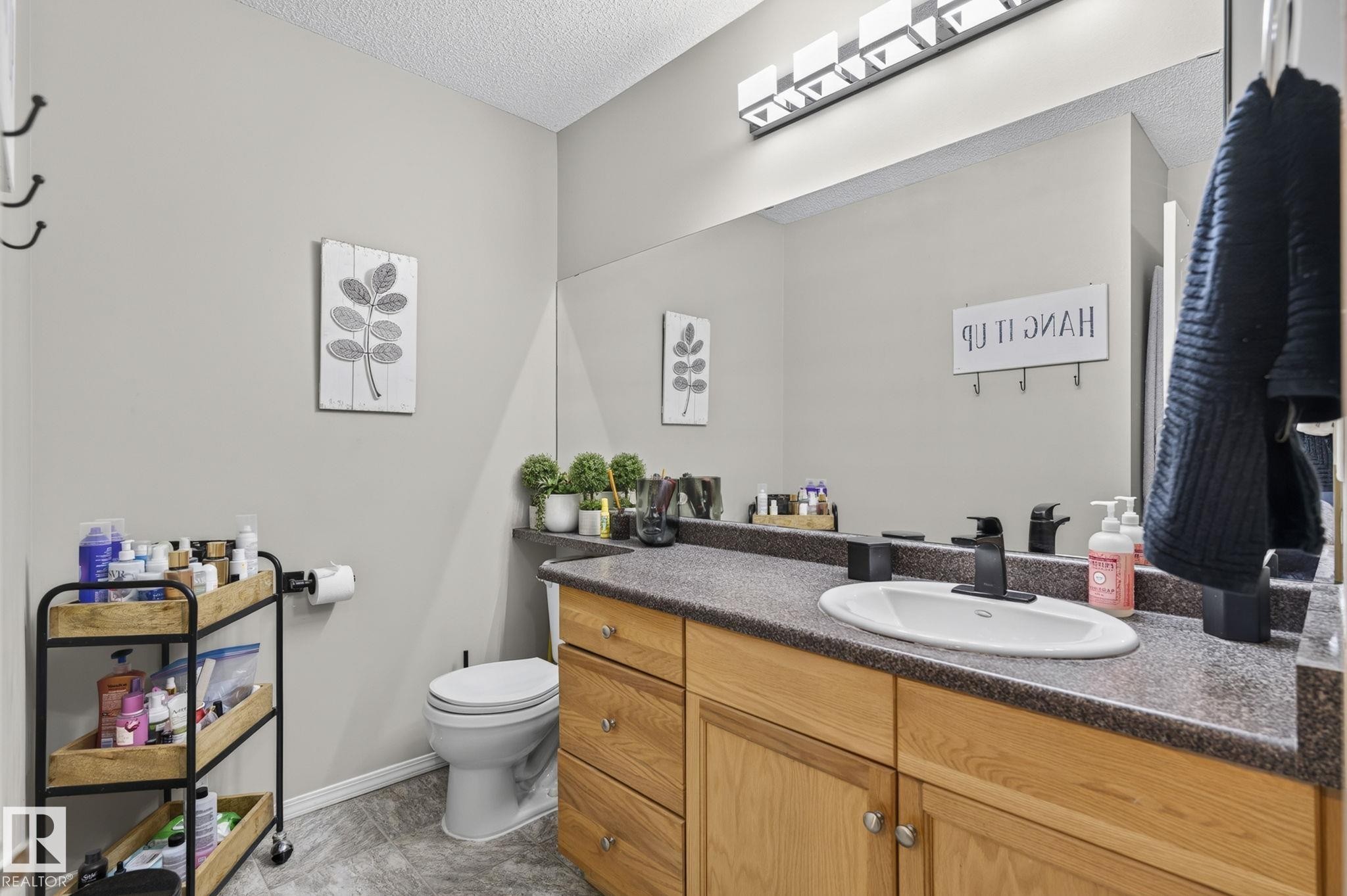 Bathroom featuring a vanity with a dark speckled countertop, an undermount sink, and a matte black faucet - 122 279 Suder Greens Drive, Edmonton, AB