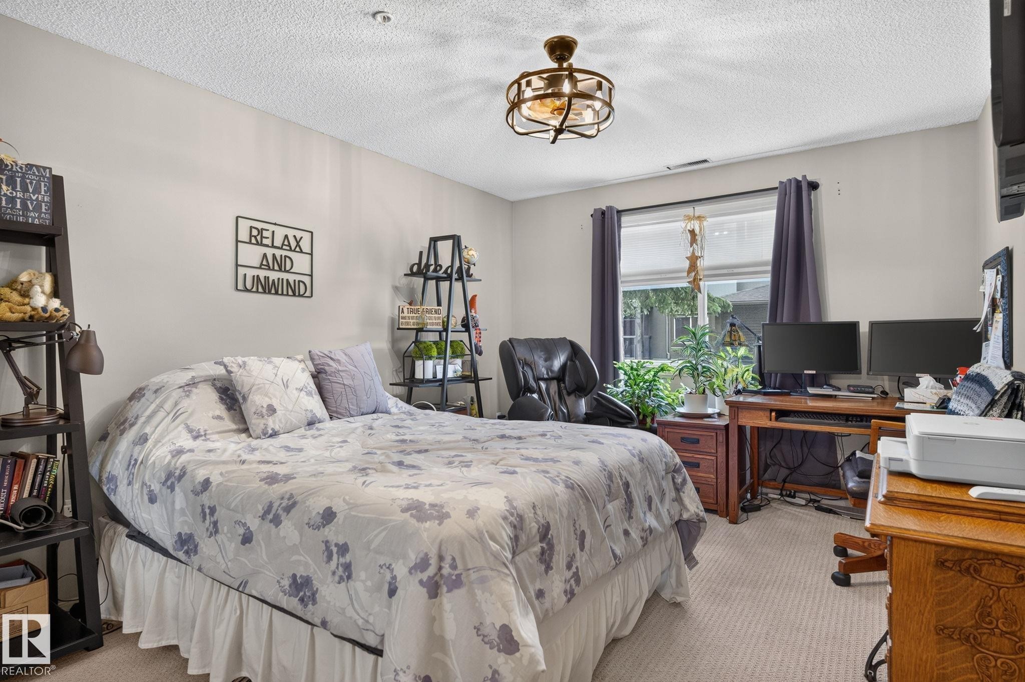 Carpeted room featuring a window with dark drapery, a ceiling-mounted light fixture, and light-toned walls - 122 279 Suder Greens Drive, Edmonton, AB