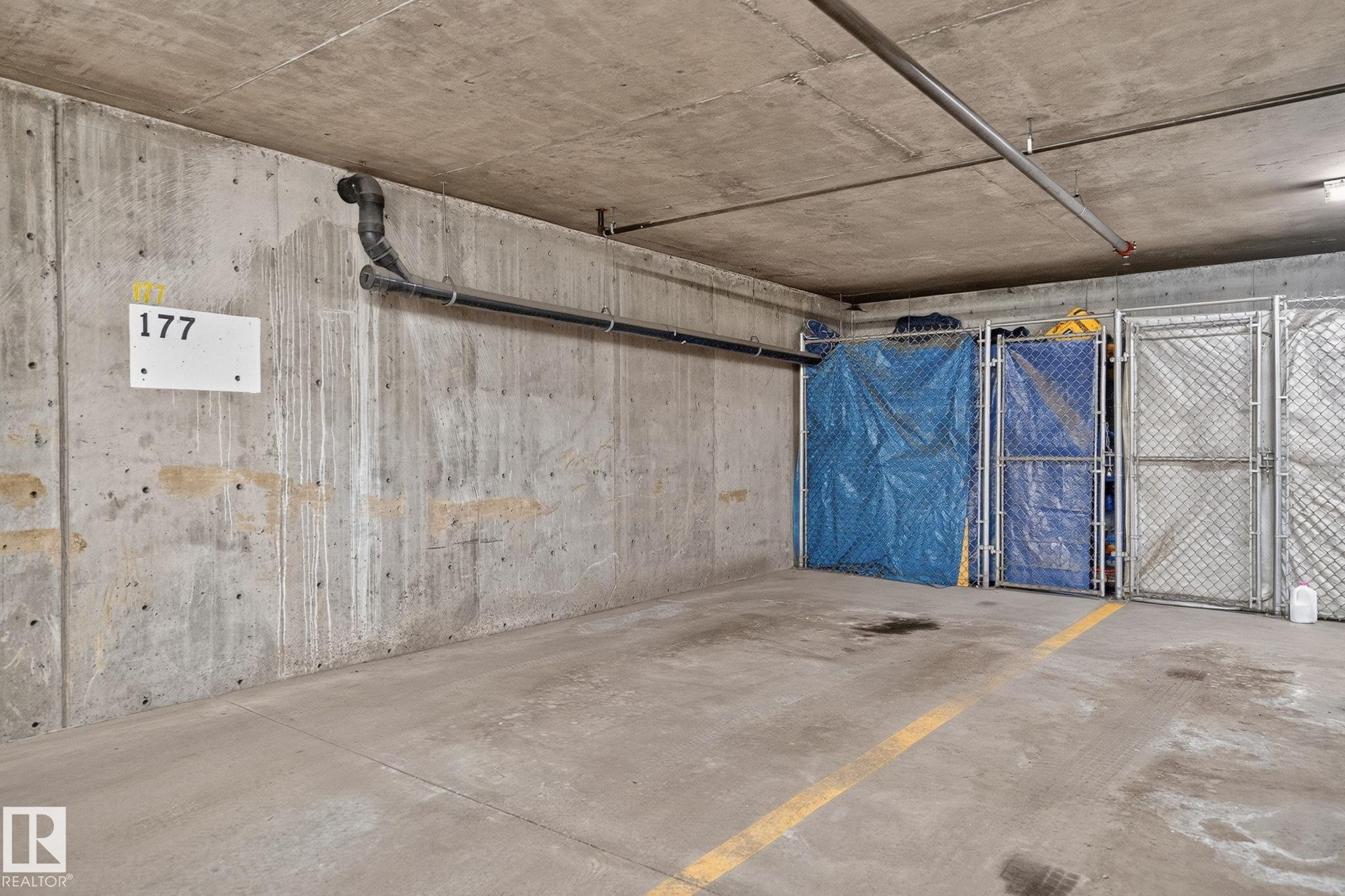 Dedicated parking space featuring a concrete floor with painted yellow lines - 122 279 Suder Greens Drive, Edmonton, AB