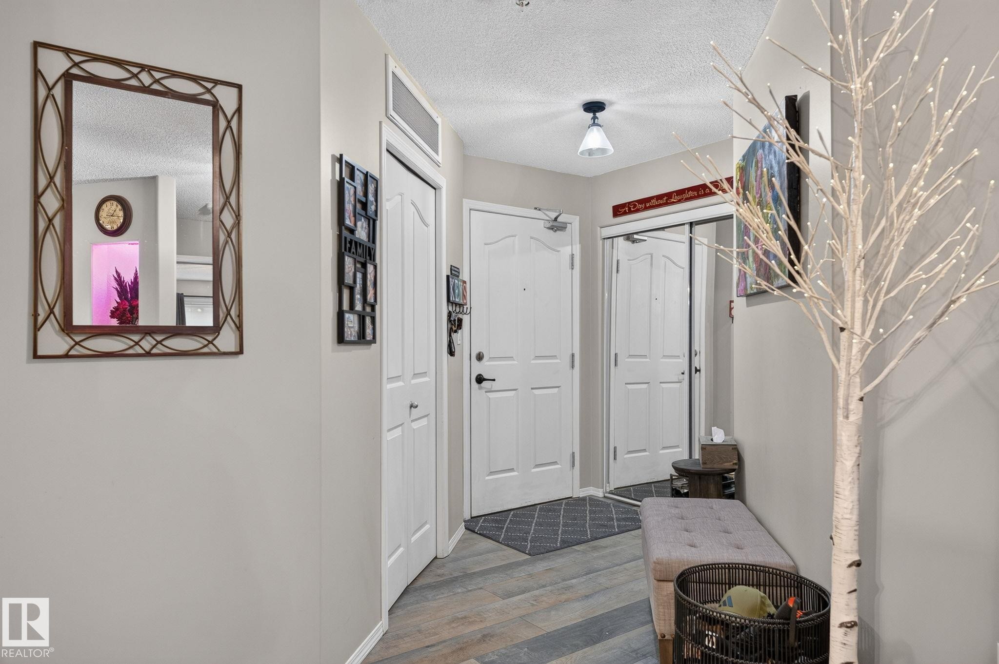 Entryway featuring wood-finish flooring, white panel doors, and a built-in overhead light fixture - 122 279 Suder Greens Drive, Edmonton, AB