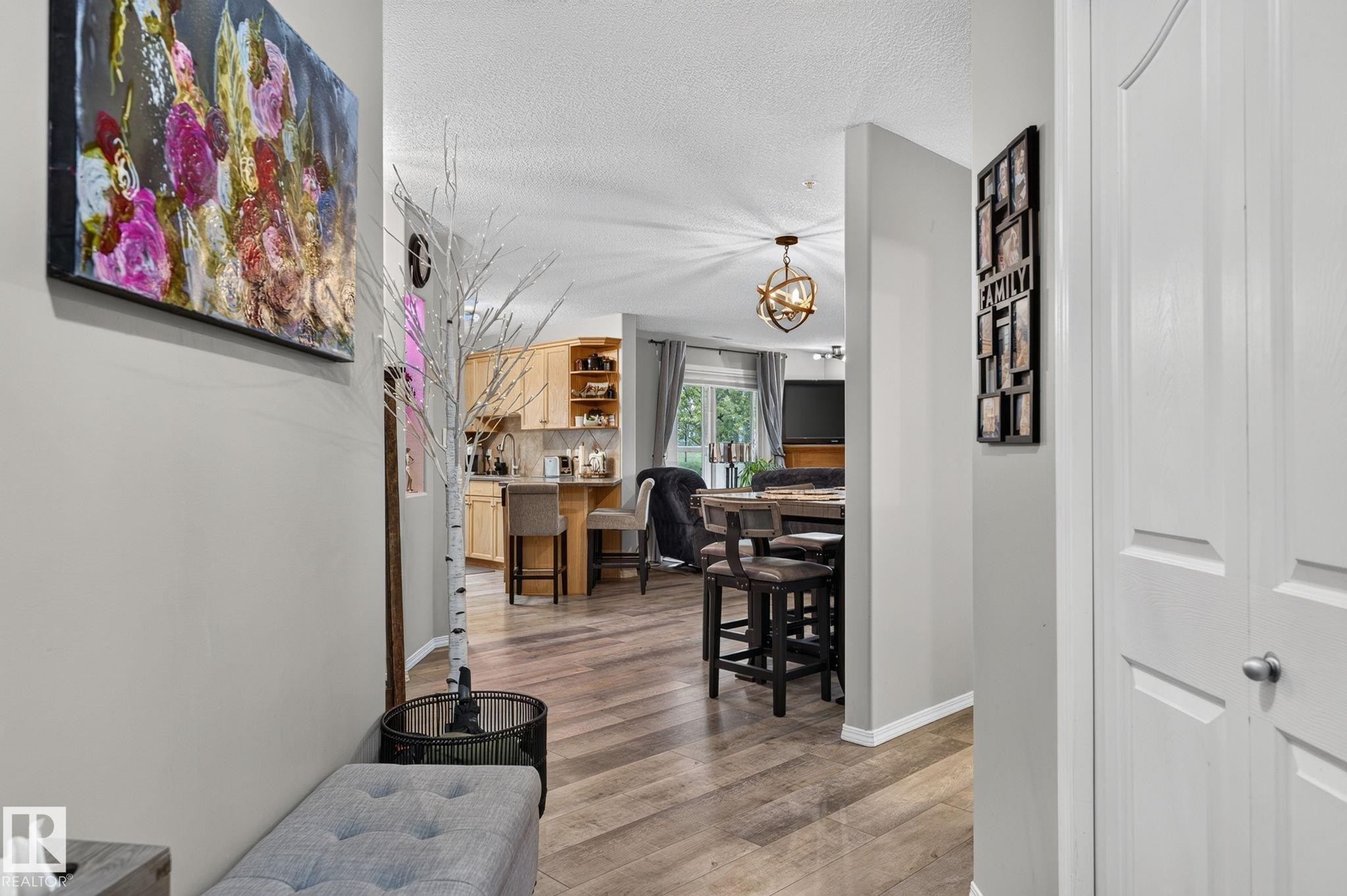 Hallway with light gray walls, wood-finish flooring, and white bi-fold closet doors - 122 279 Suder Greens Drive, Edmonton, AB