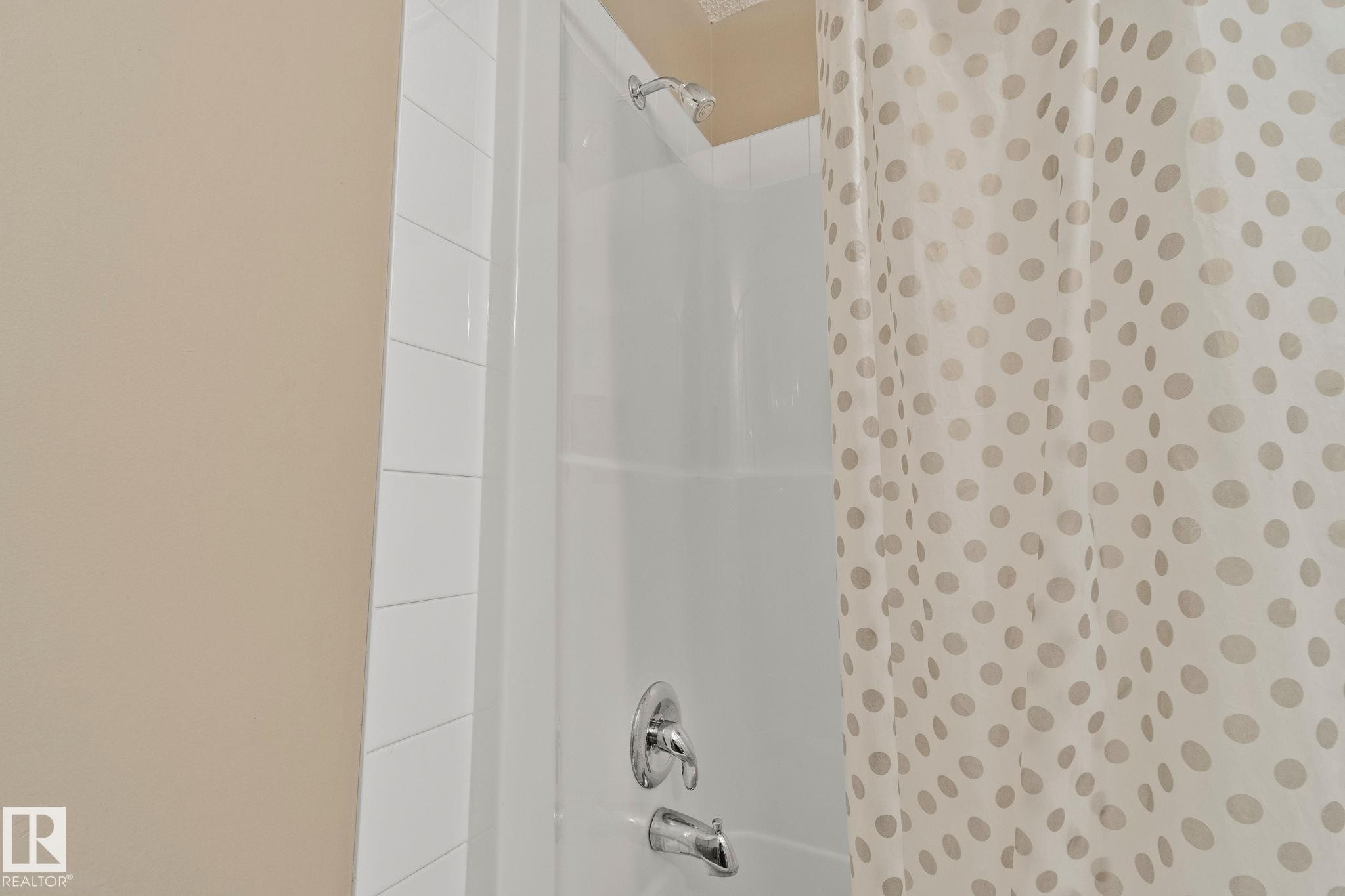 White subway tile surround within a shower-over-tub combination featuring chrome fixtures - 209 5280 Terwillegar Boulevard, Edmonton, AB - Indoor Photo Showing Bathroom