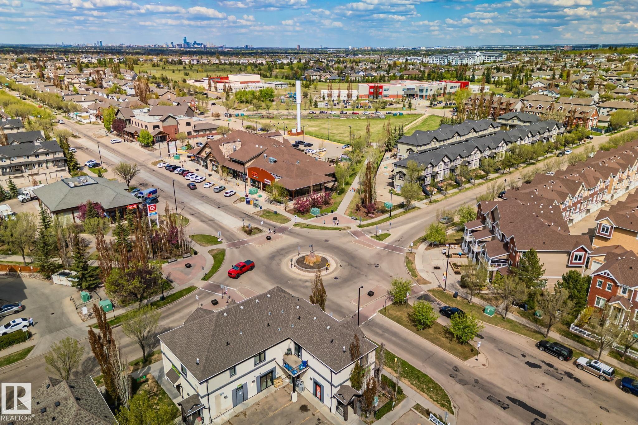 Aerial perspective showcasing a mixed-use development with commercial buildings, townhomes, and single-family residences - 209 5280 Terwillegar Boulevard, Edmonton, AB - Outdoor With View