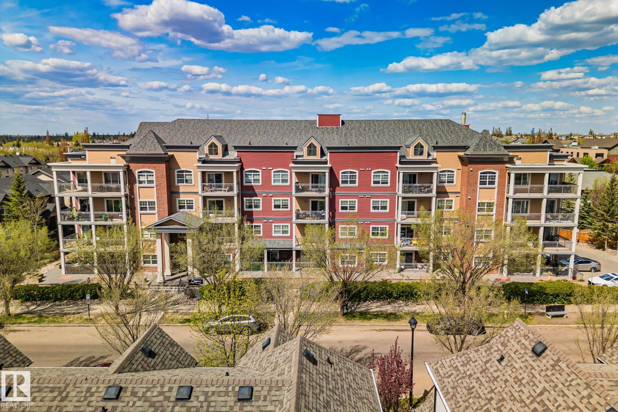 Multi-story residential building featuring a varied facade with red and tan sections - 209 5280 Terwillegar Boulevard, Edmonton, AB - Outdoor With Balcony