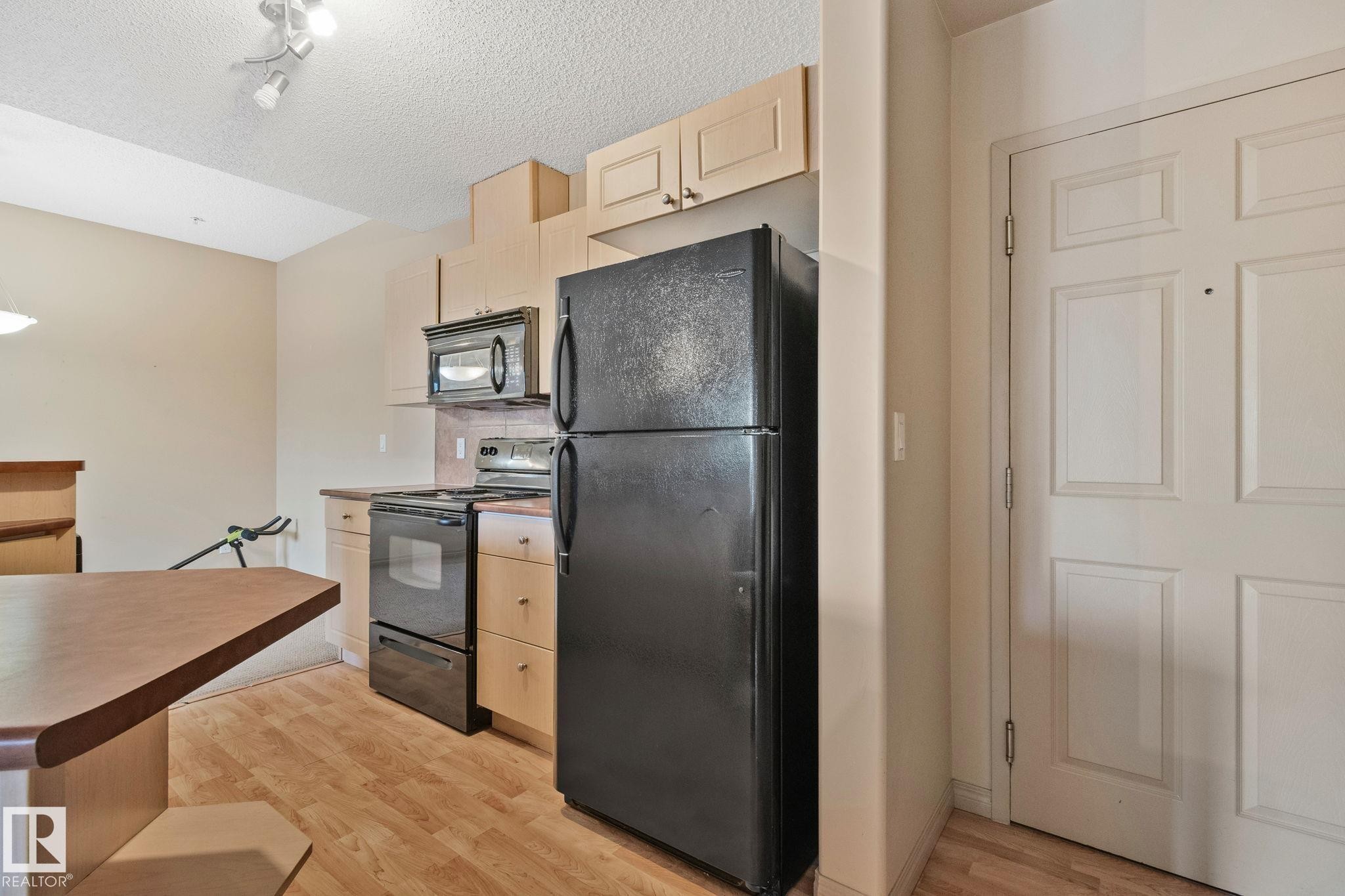 Kitchen featuring wood-finish flooring and light wood cabinetry - 209 5280 Terwillegar Boulevard, Edmonton, AB - Indoor Photo Showing Kitchen