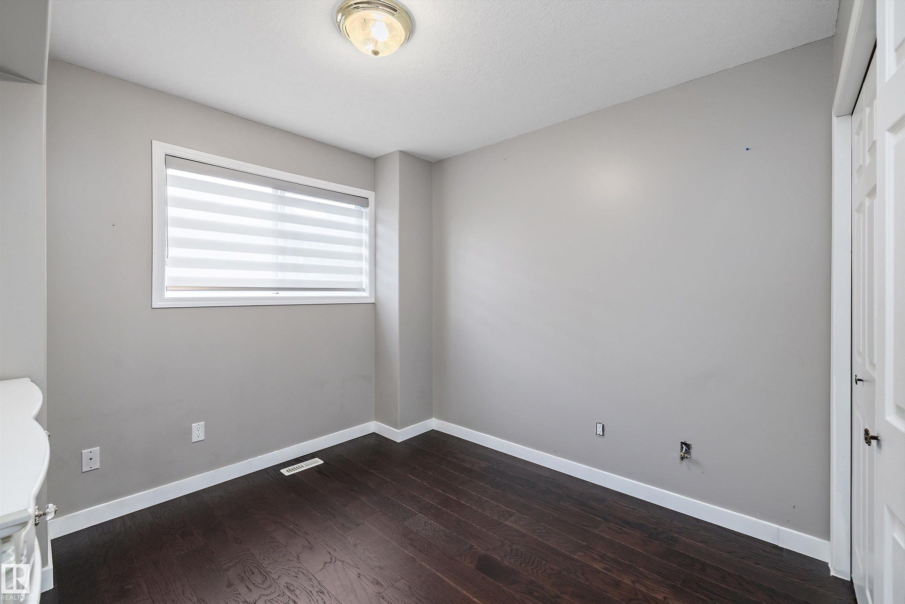 Neutral wall finishes with dark wood-finish flooring - 4831 154 Avenue, Edmonton, AB