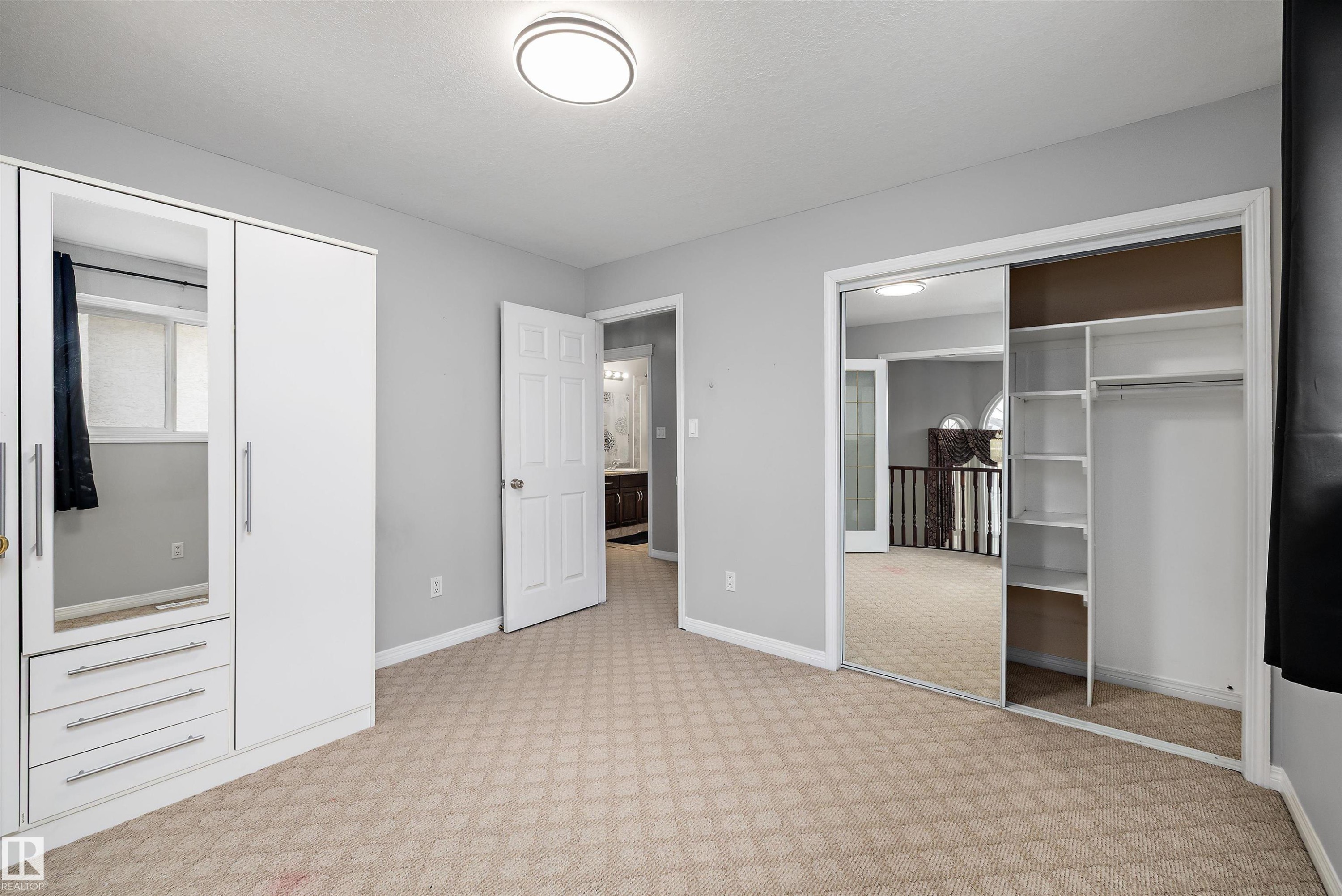 Bedroom featuring patterned carpet, light grey walls, and a flush mount ceiling light - 4831 154 Avenue, Edmonton, AB