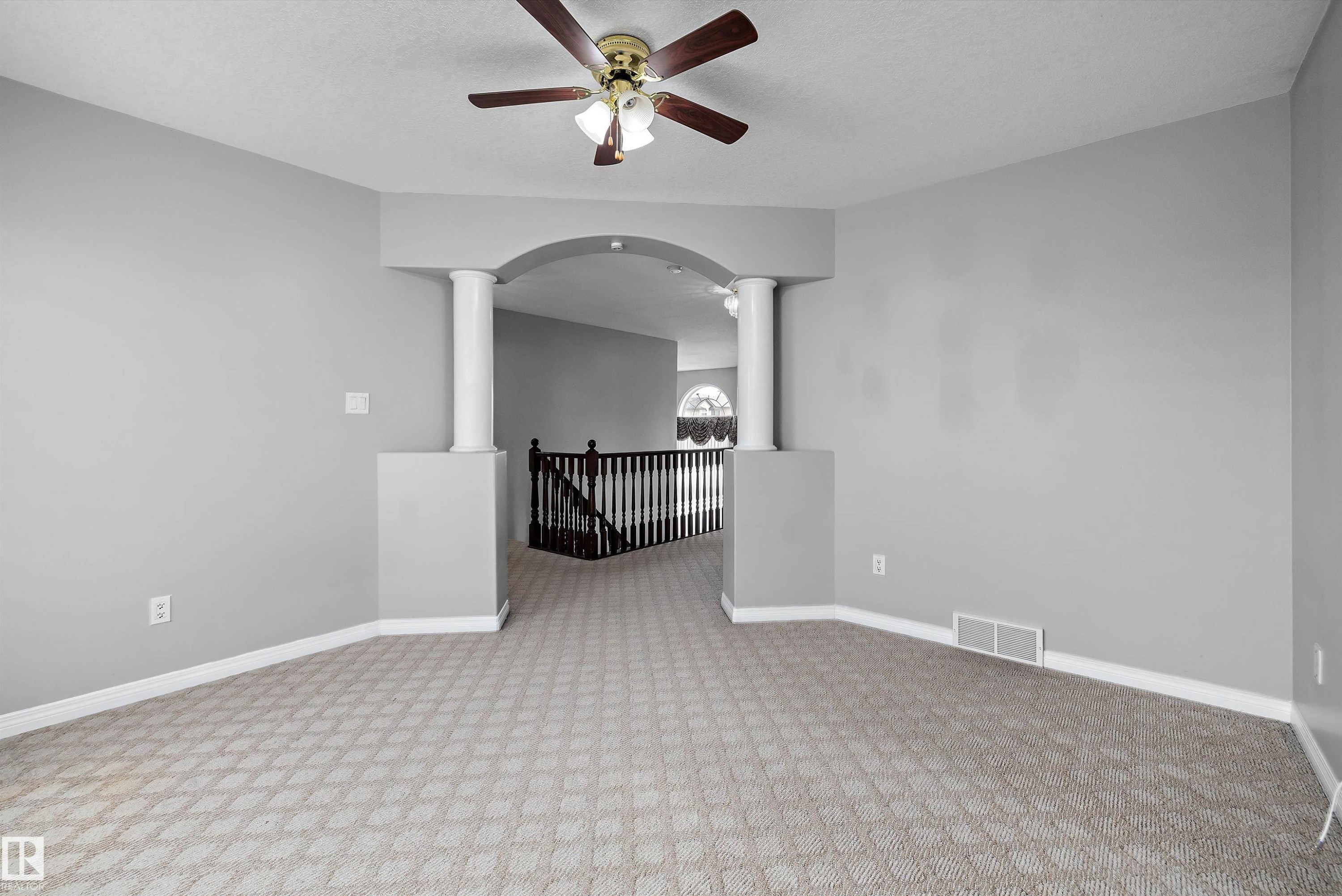 Carpeted interior space featuring an architectural archway with decorative columns - 4831 154 Avenue, Edmonton, AB
