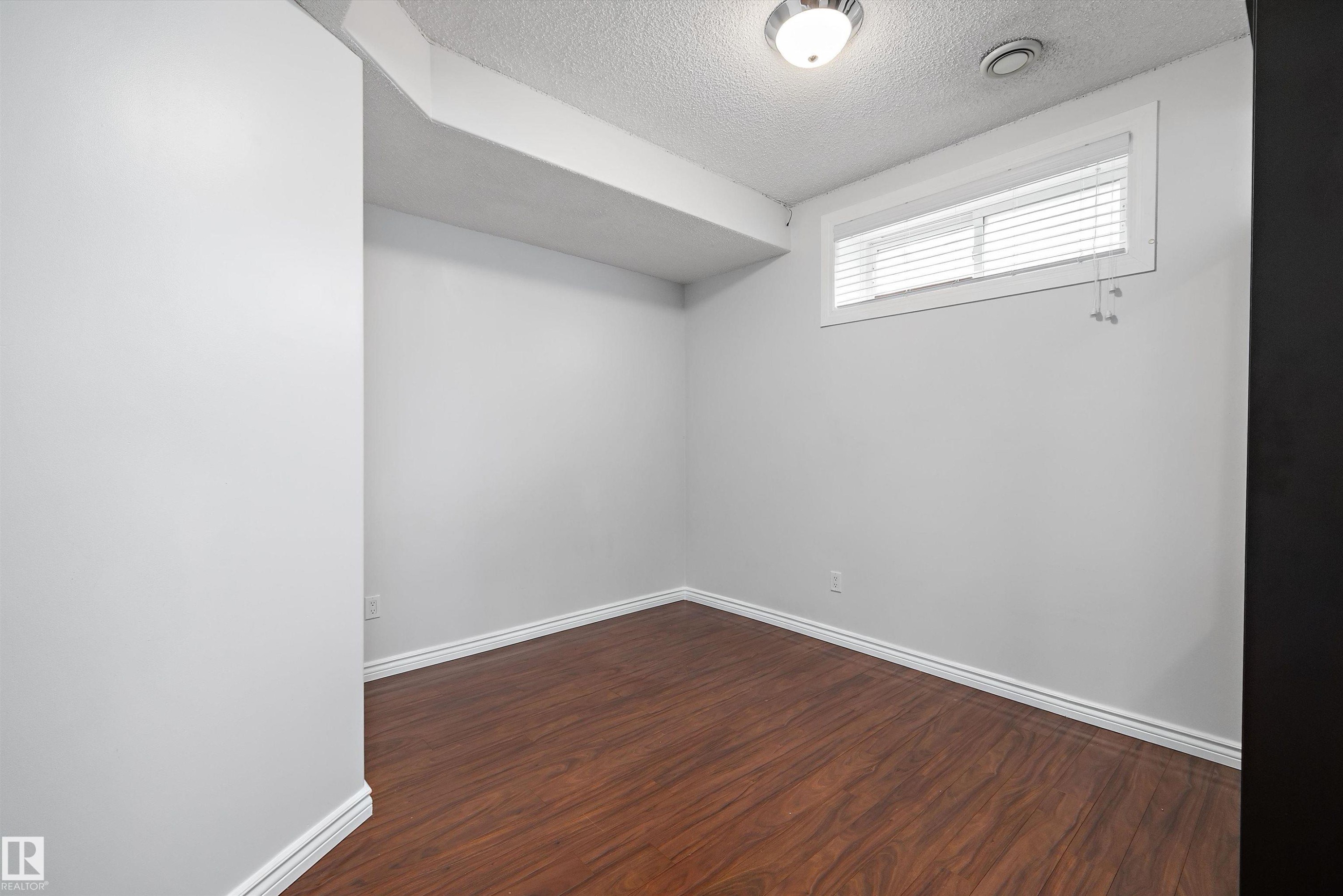 Room featuring wood-finish flooring, white baseboards, and light gray painted walls - 4831 154 Avenue, Edmonton, AB