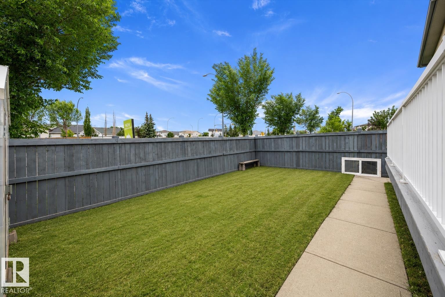 Private backyard featuring a well-maintained lawn, a paved walkway, and a dark stained wooden fence - 4831 154 Avenue, Edmonton, AB