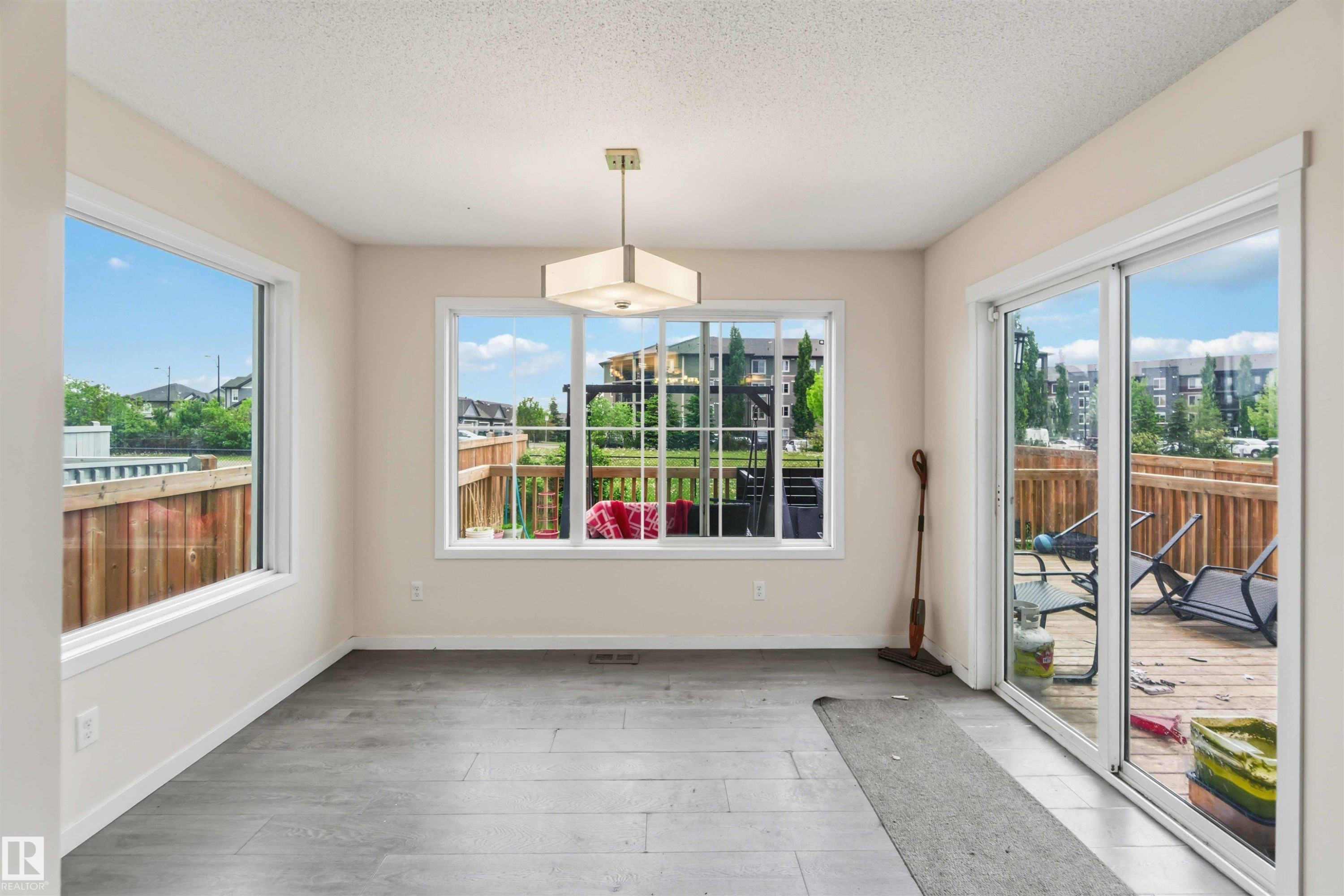 Spacious room featuring wood-finish flooring, light-colored walls, and a contemporary ceiling fixture - 5120 19 Avenue, Edmonton, AB