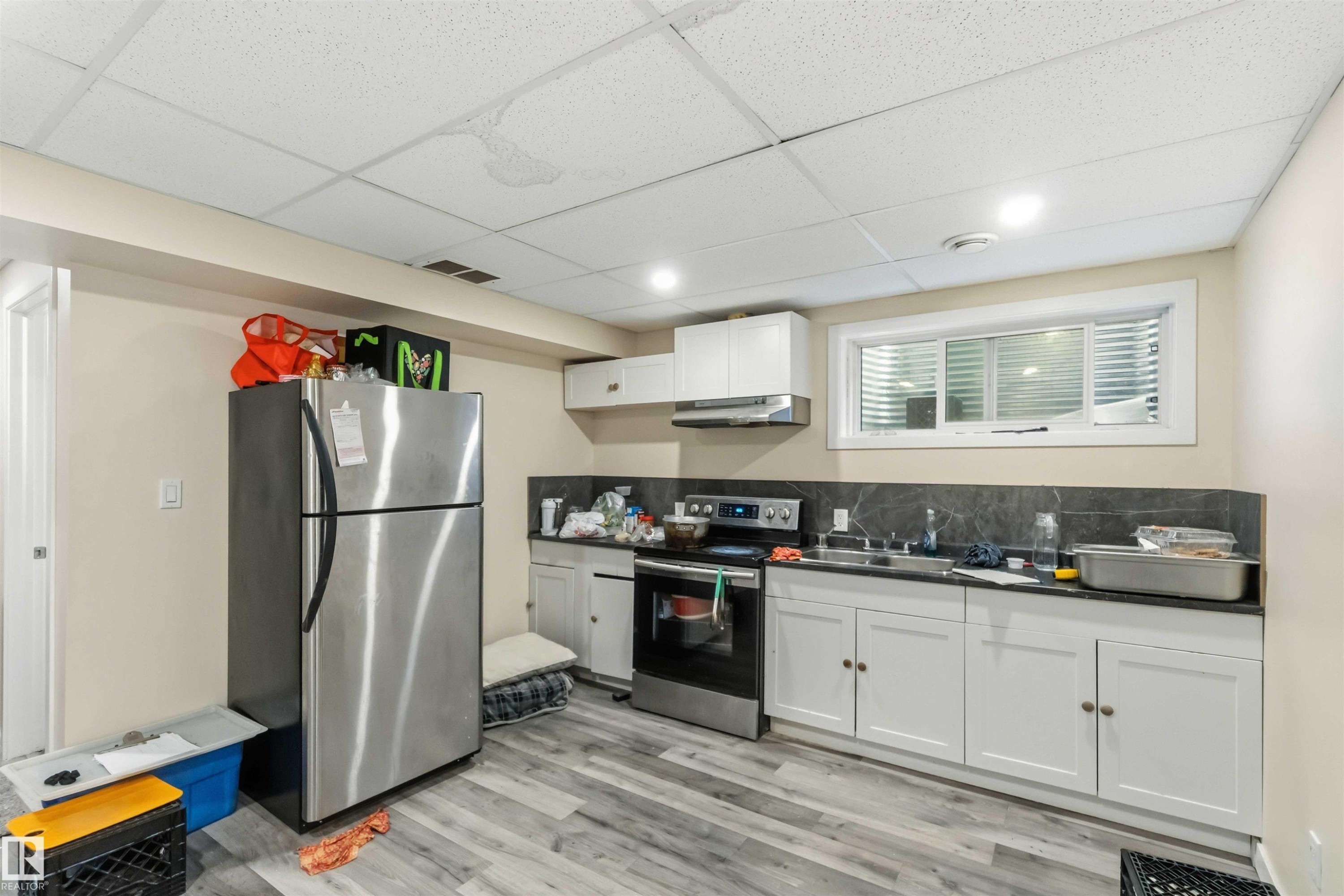 Kitchenette featuring white cabinetry, a stainless steel refrigerator, and a built-in range - 5120 19 Avenue, Edmonton, AB