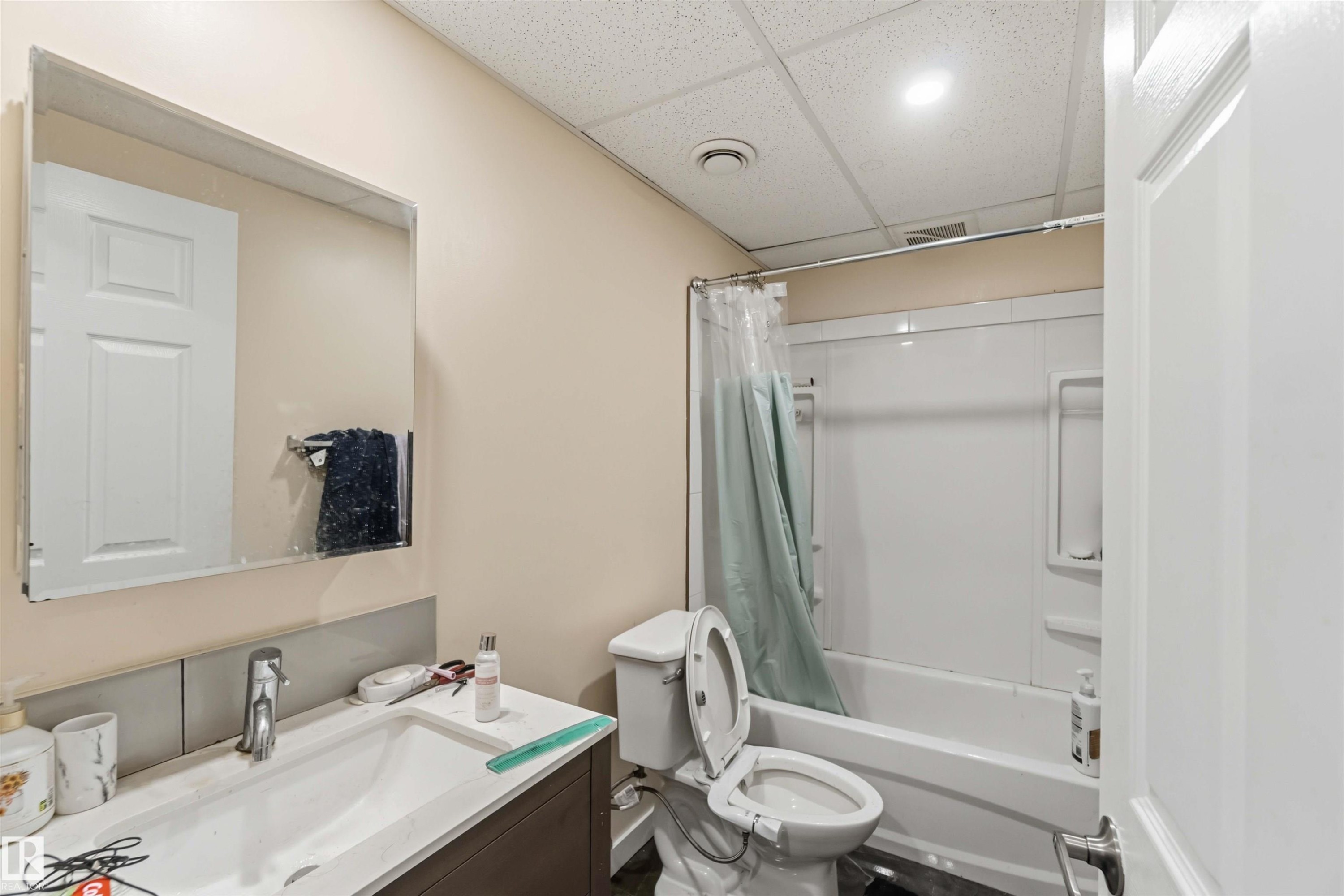 Bathroom featuring a white vanity with an integrated sink, polished chrome faucet, and a large wall-mounted mirror - 5120 19 Avenue, Edmonton, AB