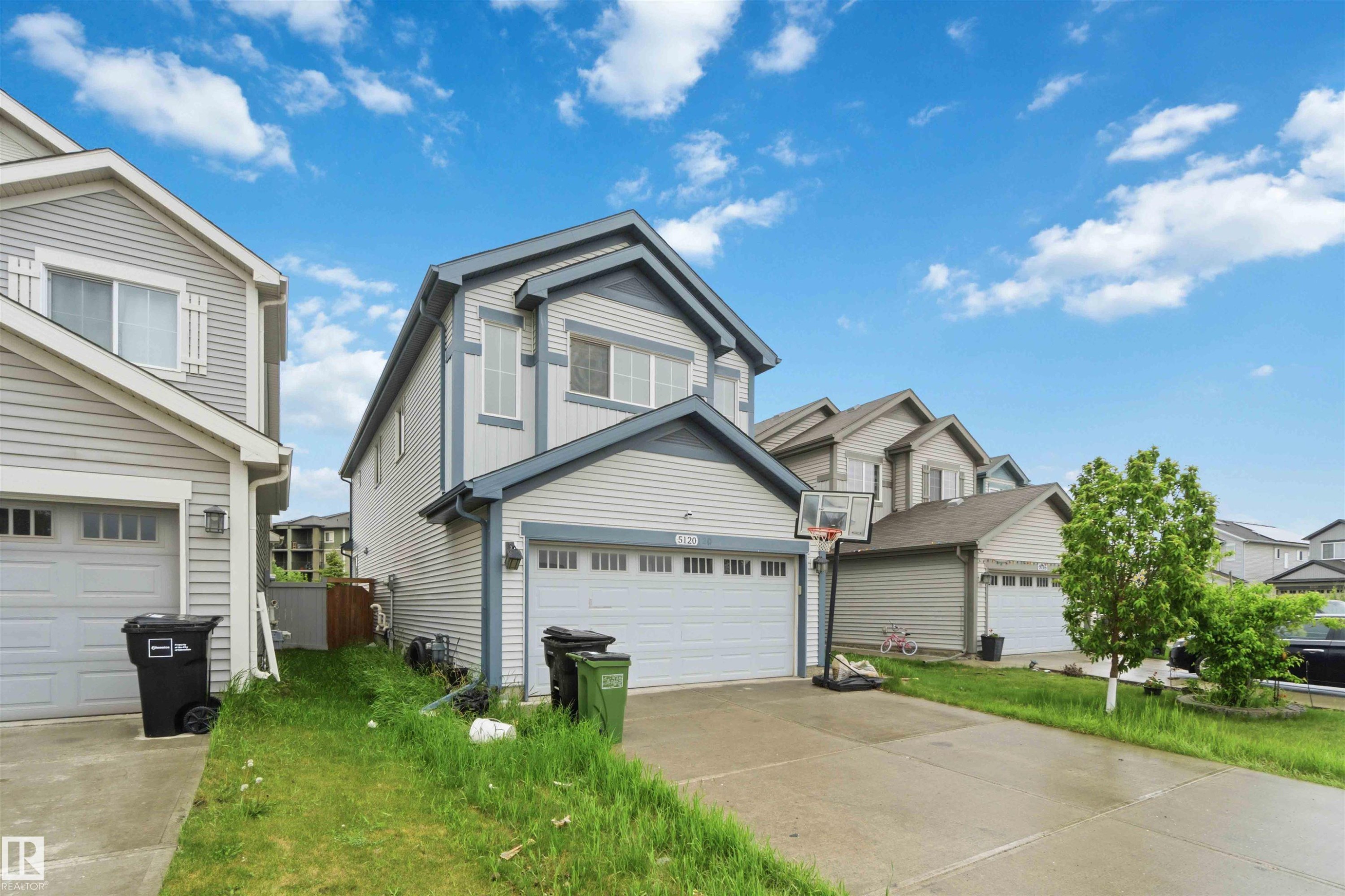 Two-story residence featuring light gray siding with dark gray trim, an attached two-car garage, and a concrete driveway - 5120 19 Avenue, Edmonton, AB