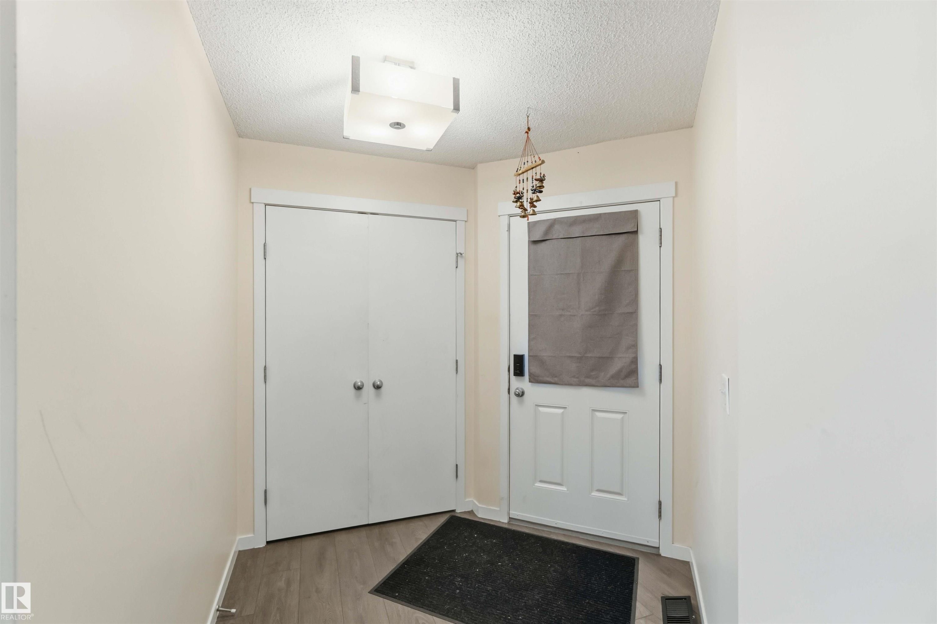 Entryway featuring light-toned walls, wood-finish flooring, and a flush-mount ceiling fixture - 5120 19 Avenue, Edmonton, AB