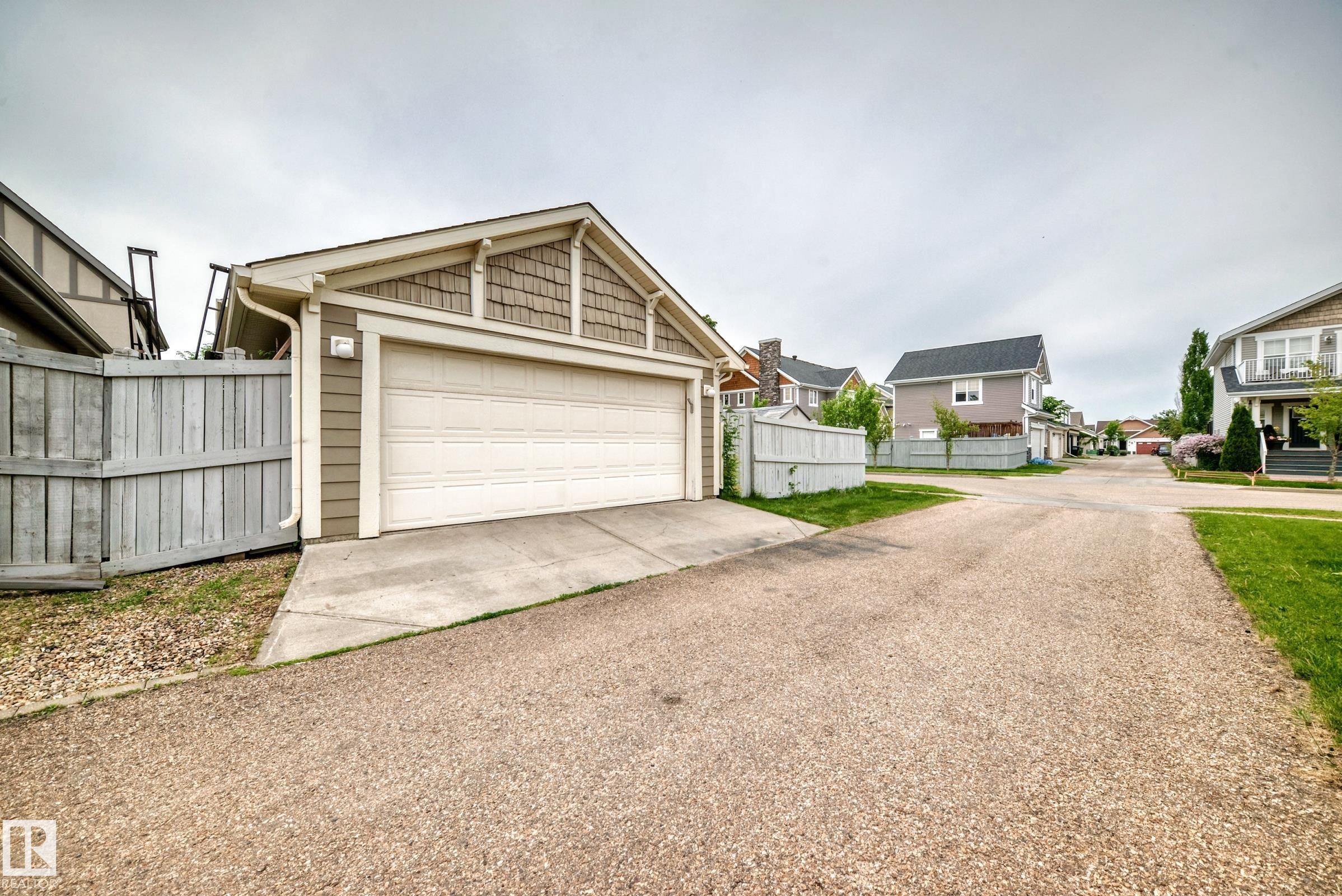 Detached garage featuring a white sectional door, horizontal siding, and decorative shake shingles on the gable - 2523 Pegasus Boulevard, Edmonton, AB